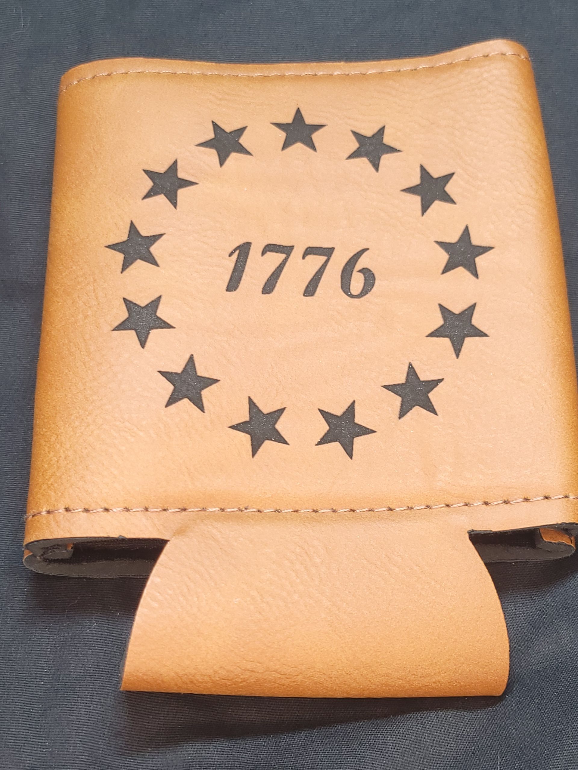 1776 is engraved on a brown leather can holder