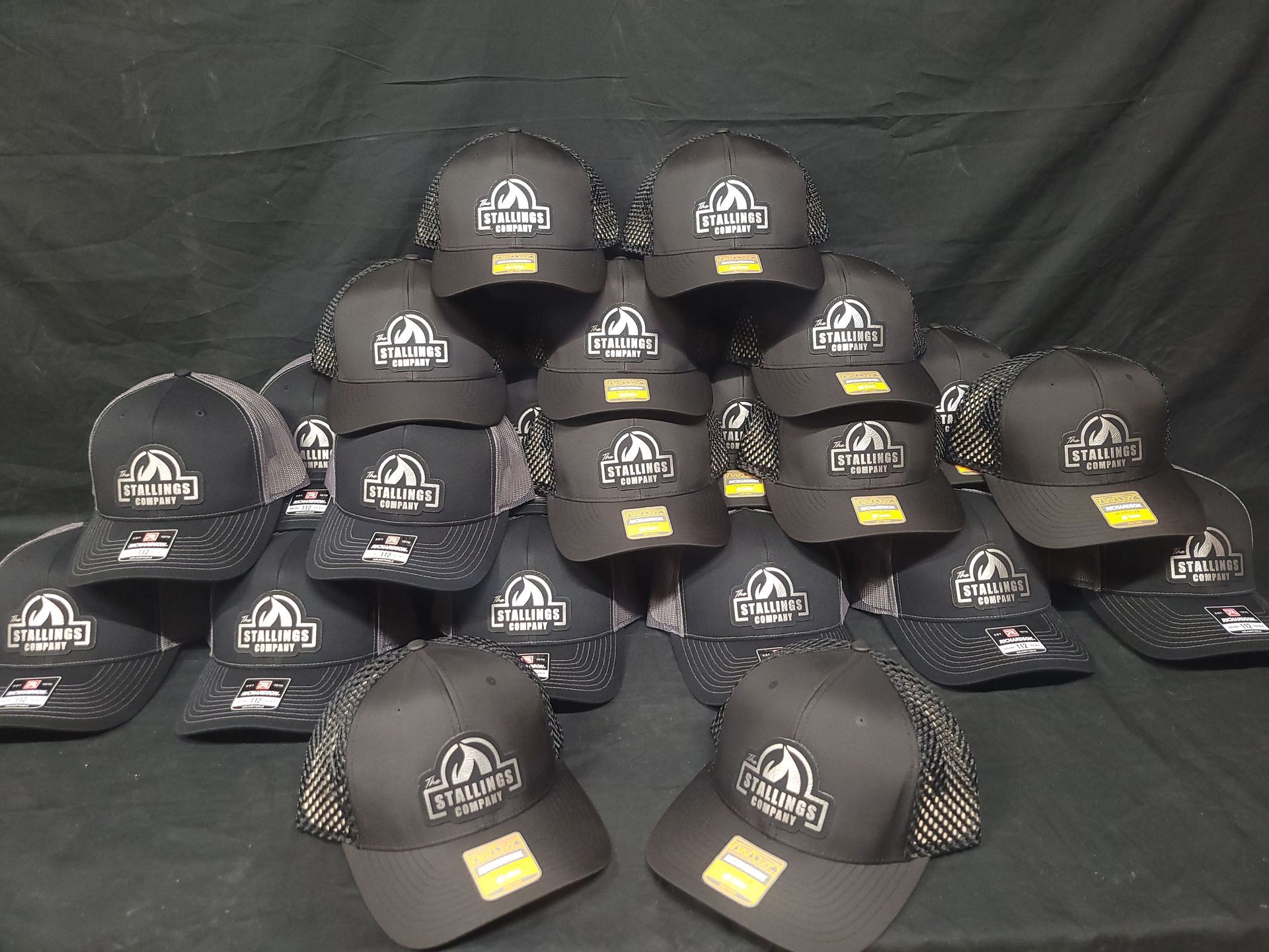 A bunch of black hats are stacked on top of each other on a table.