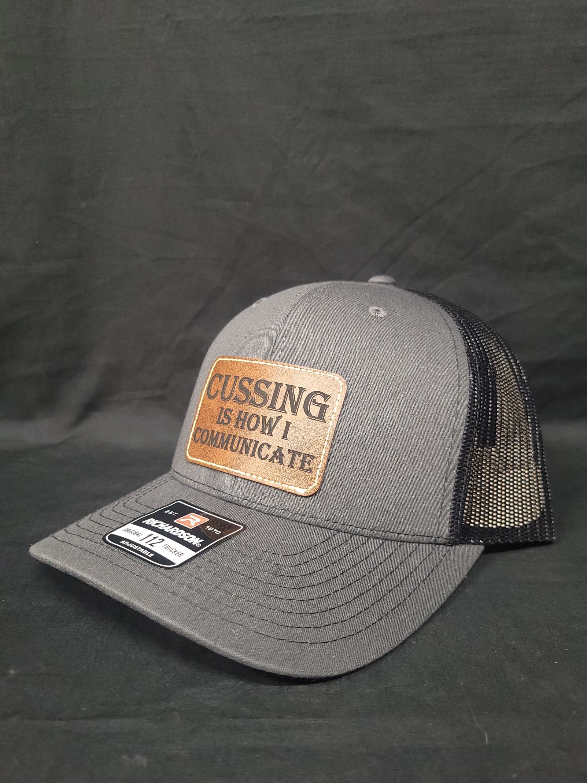 A baseball cap with a leather patch on it is sitting on a black table.