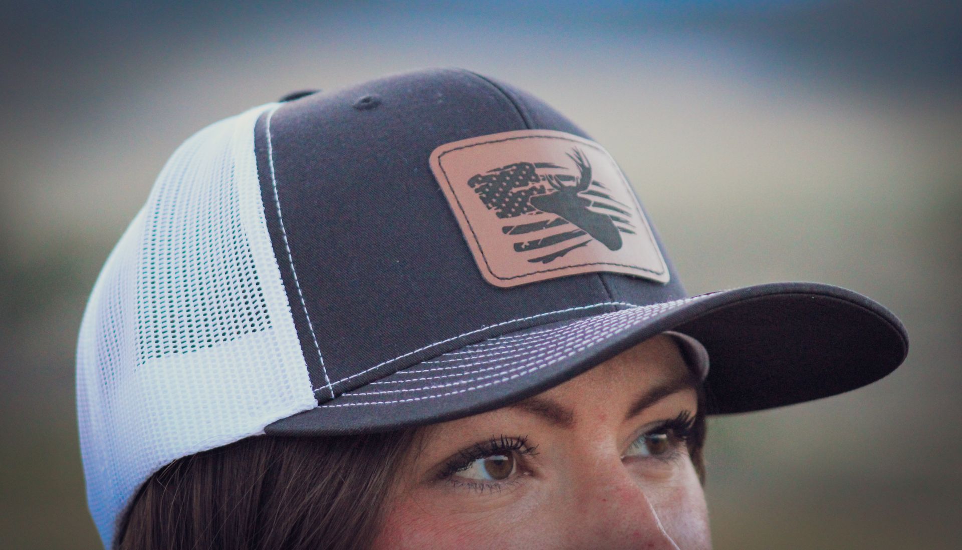 A woman wearing a black and white trucker hat with a bull on it.