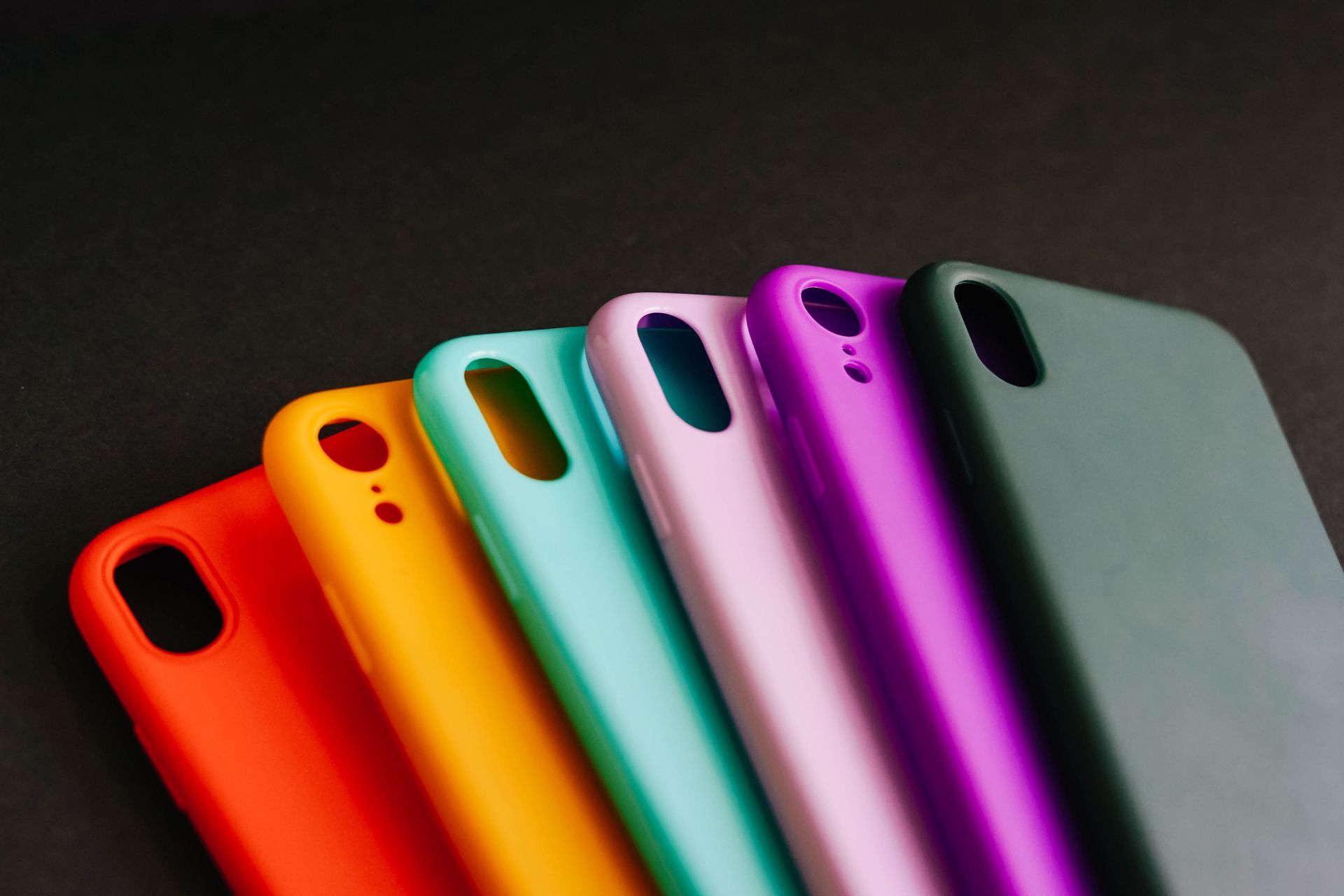 Una fila di custodie colorate per cellulari su uno sfondo nero.