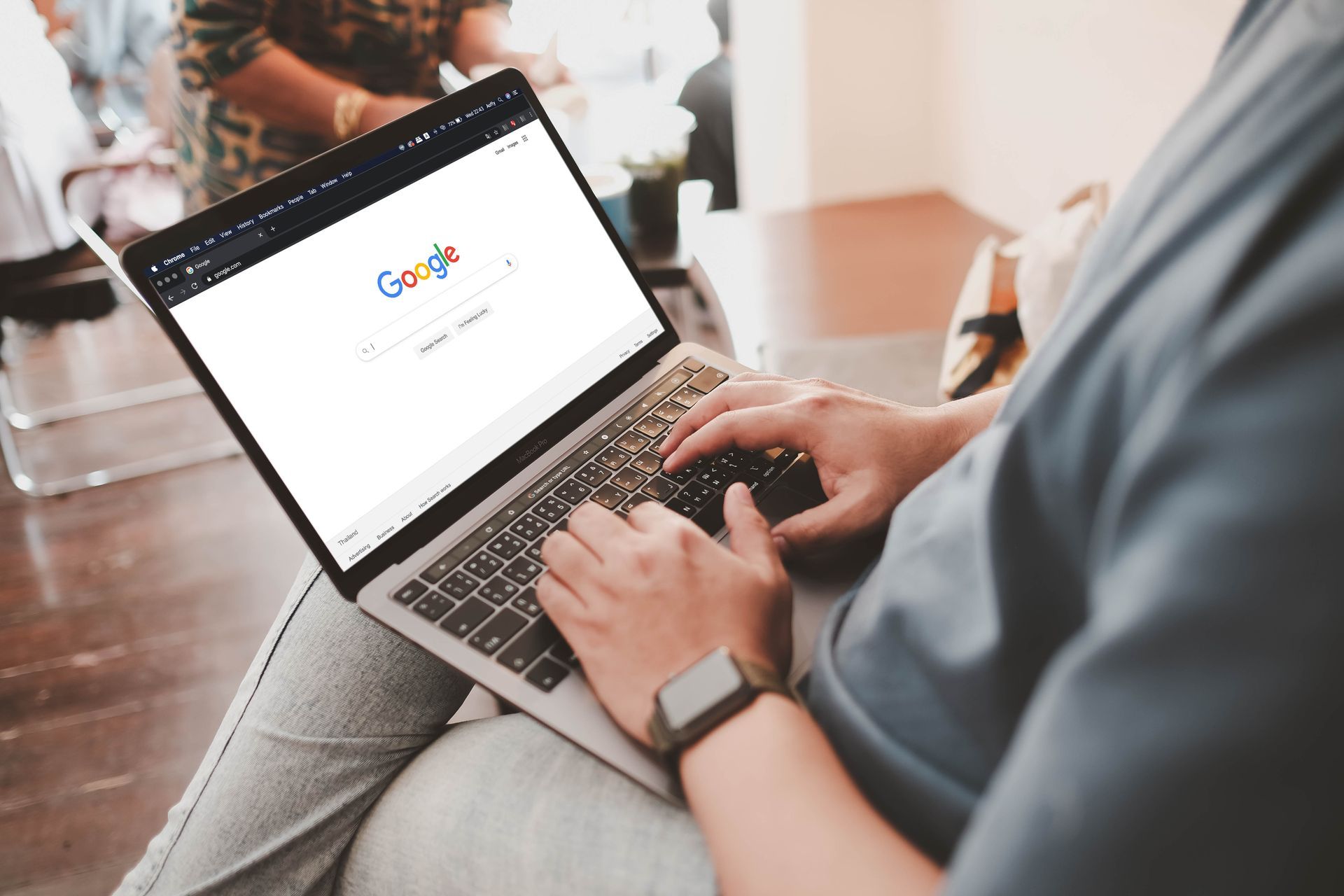 A person is sitting on a couch using a laptop computer.