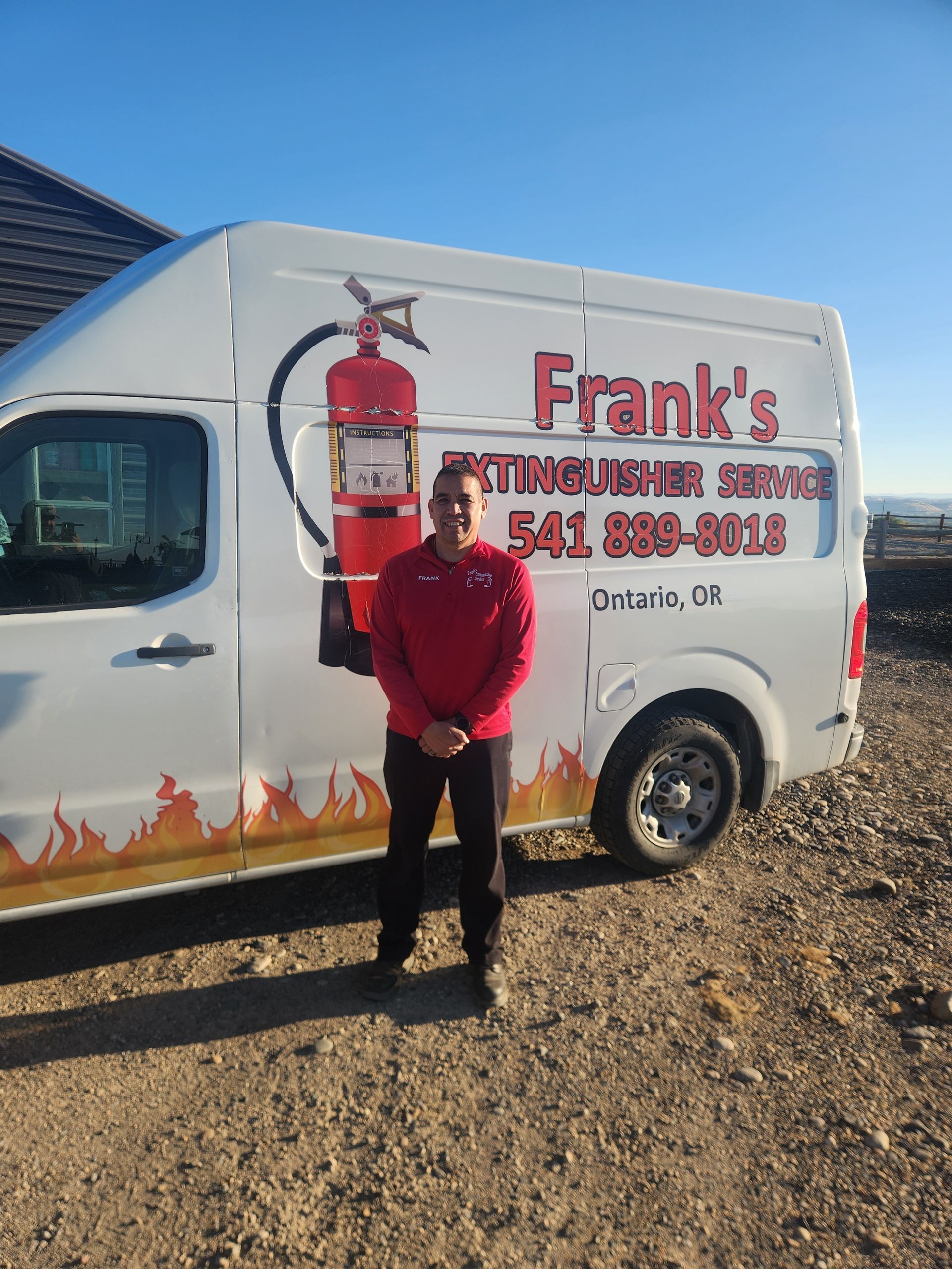 Man in red sweater stands in front of a white van with a fire extinguisher service logo.