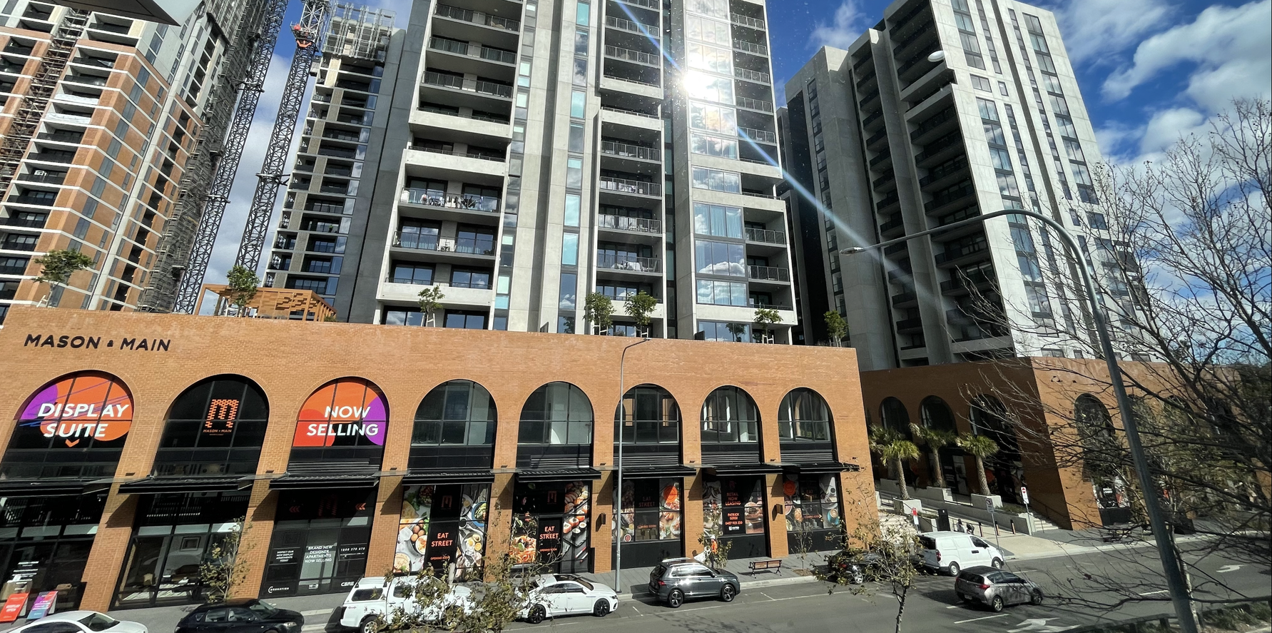A row of tall buildings with cars parked in front of them.