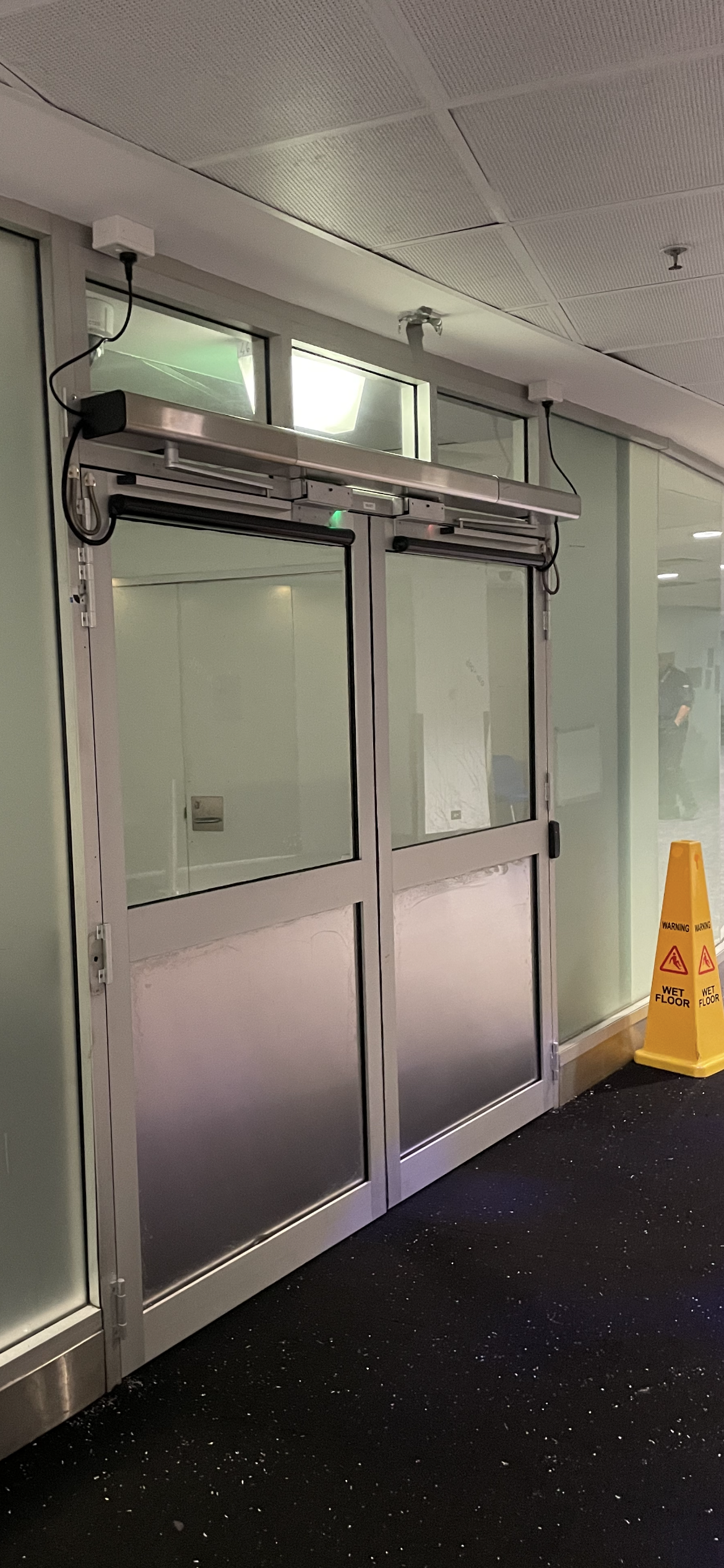 A yellow wet floor sign is next to a sliding glass door.