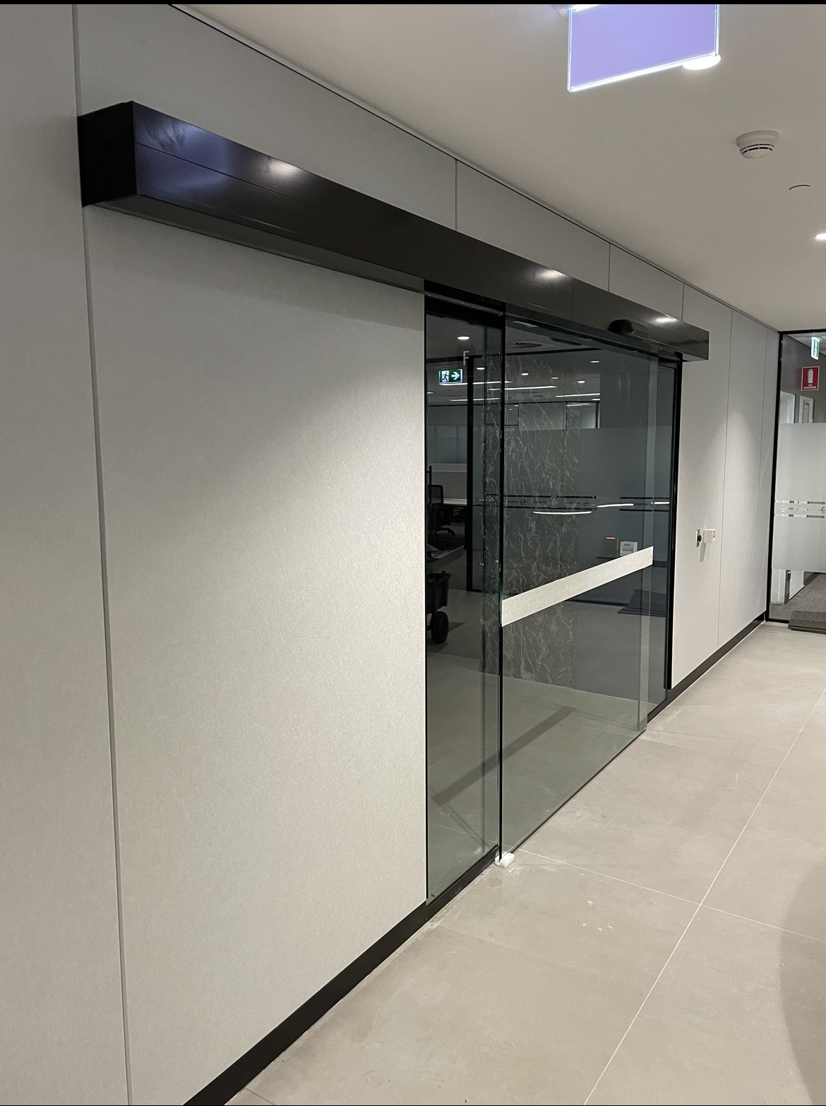 A hallway with a sliding glass door and a white wall.