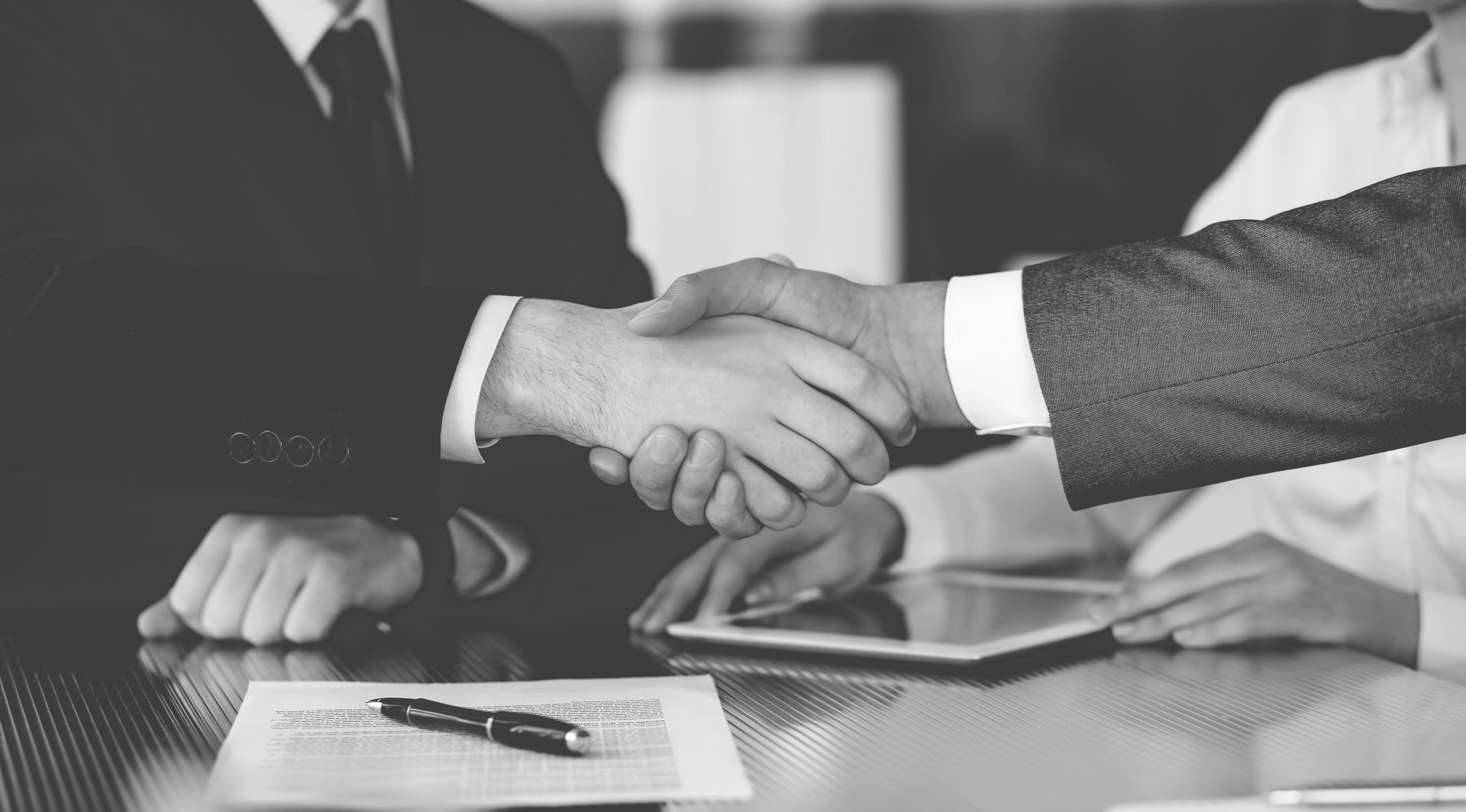 Un groupe de gens d'affaires se serrent la main autour d'une table.
