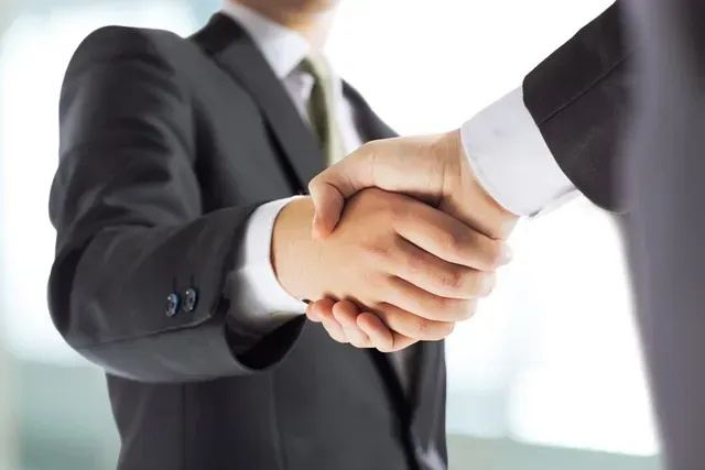 Deux hommes d'affaires en costume se serrant la main, en intérieur, gros plan.
