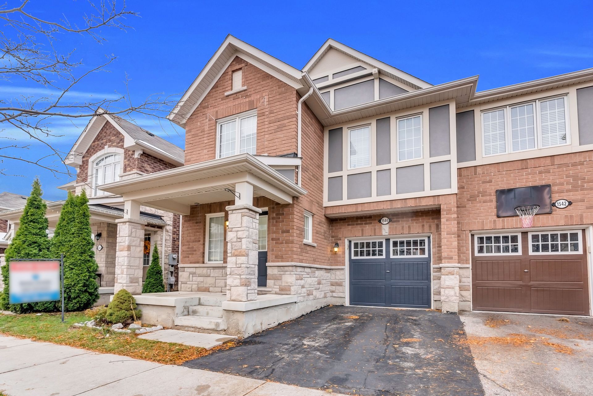 Modern brick townhouse with stone entry, garage, and driveway in a suburban neighborhood