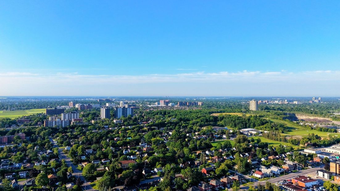 Aerial view of a green suburban cityscape with scattered high-rises under a clear blue sky