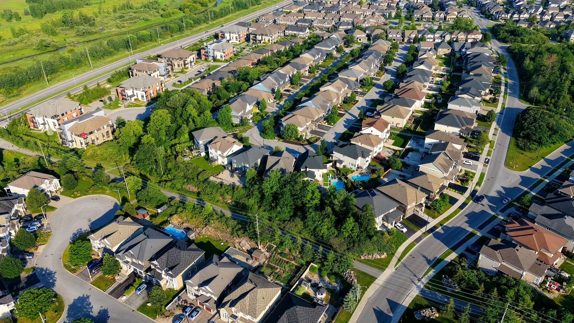 Aerial view of a suburban neighborhood with rows of houses, trees, and winding streets.