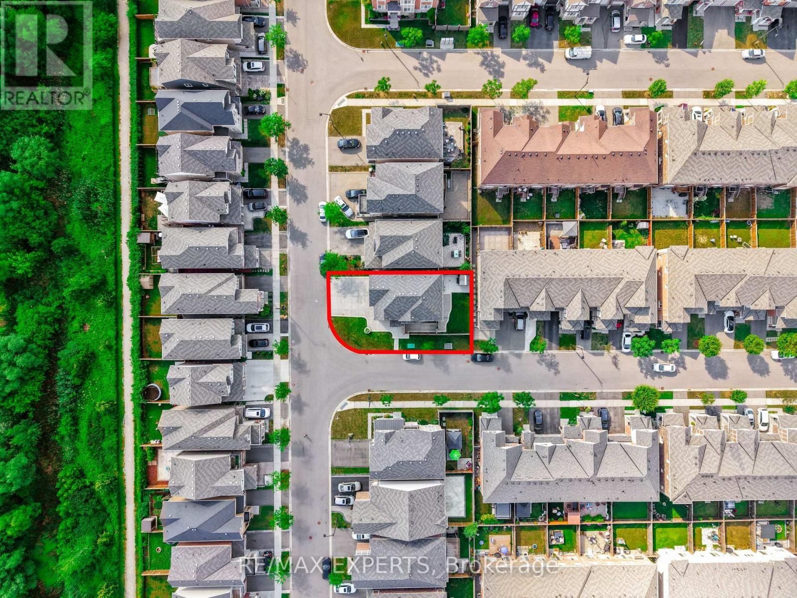 Aerial view of a suburban neighborhood with rows of houses, streets, and green trees.