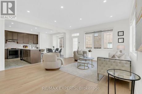 Bright open-concept living room and kitchen with light wood floors, white walls, and gray accents