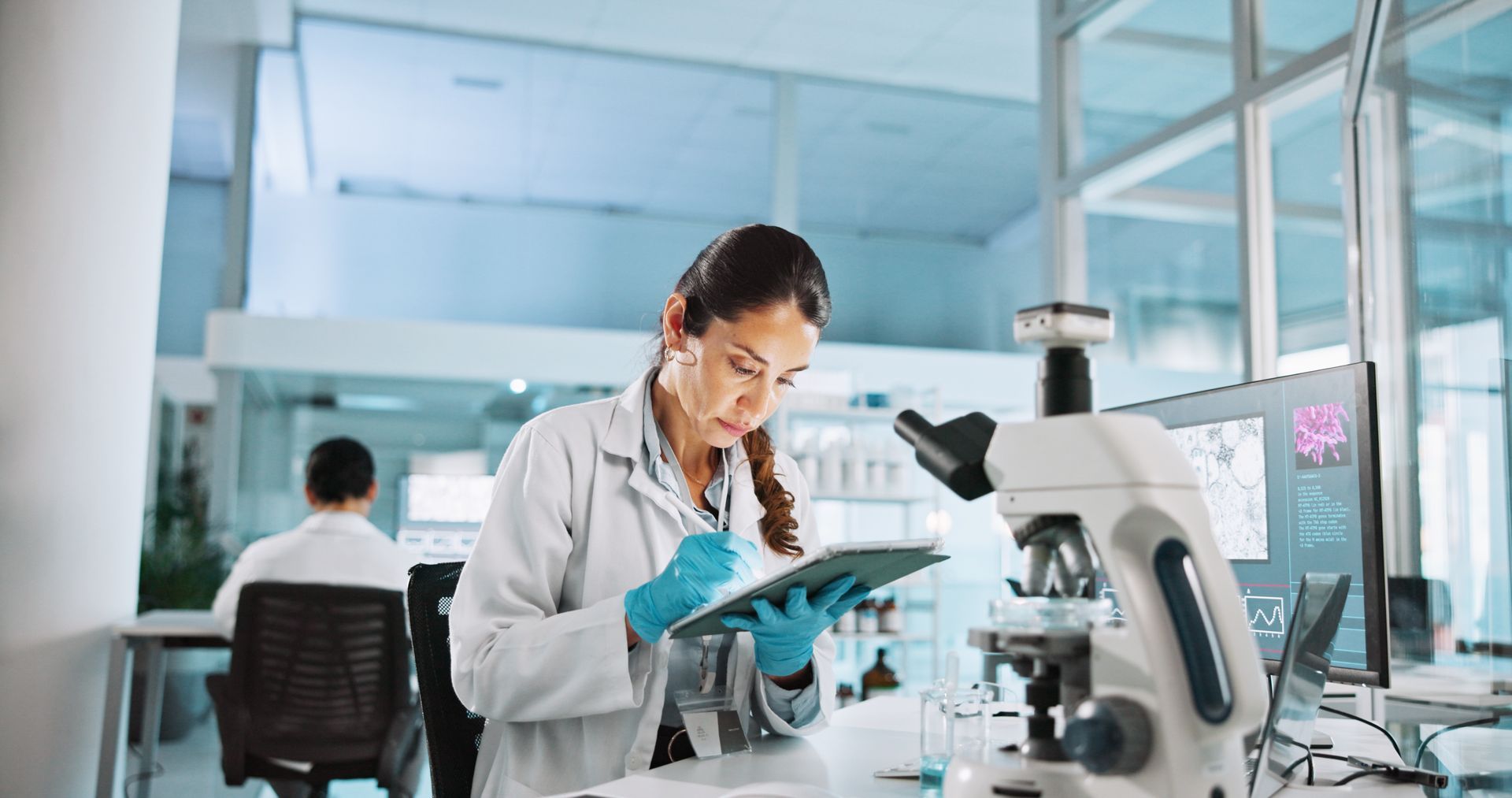 Scientist in a lab coat using a microscope in a bright laboratory