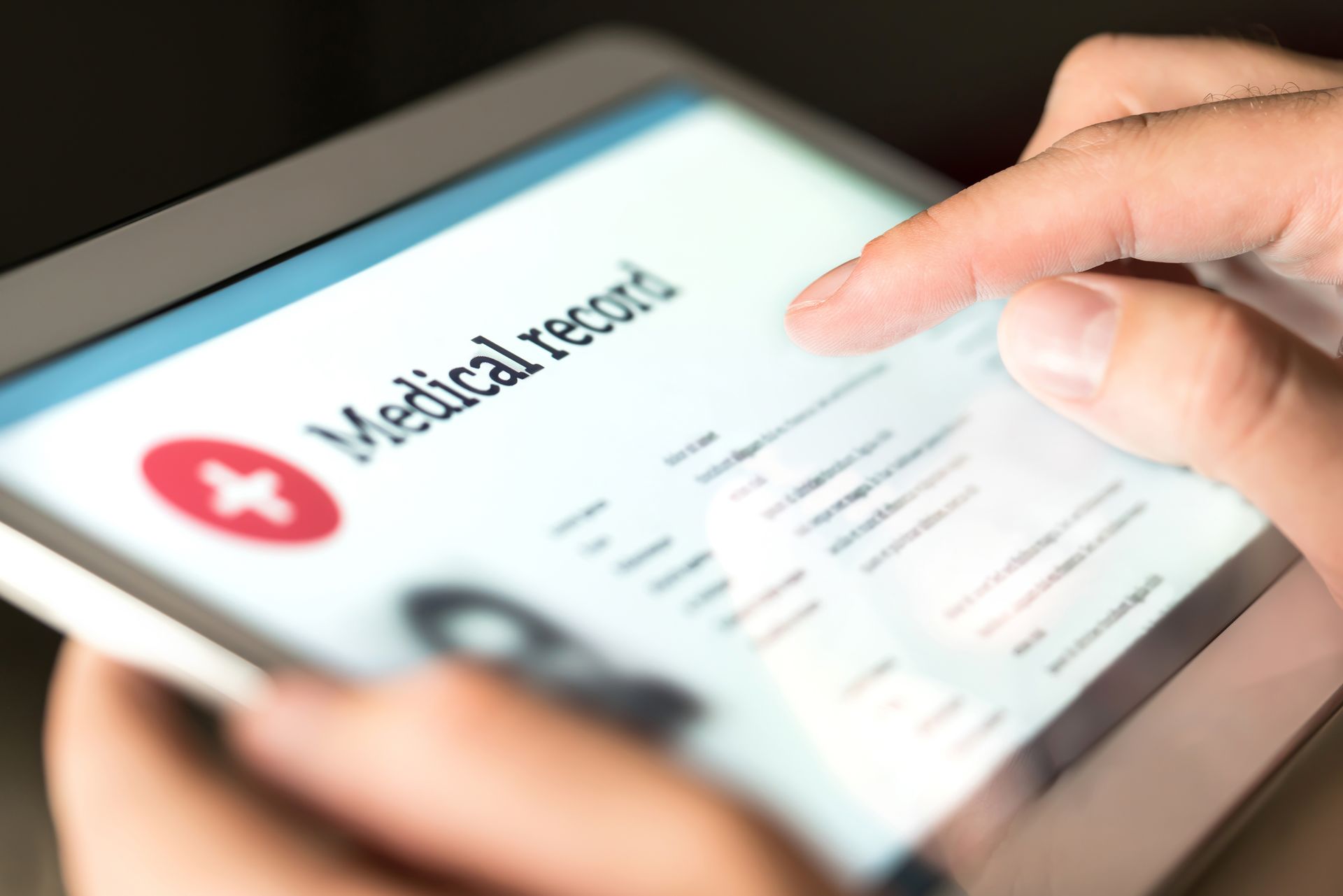 Hand holding a tablet showing a medical record app screen