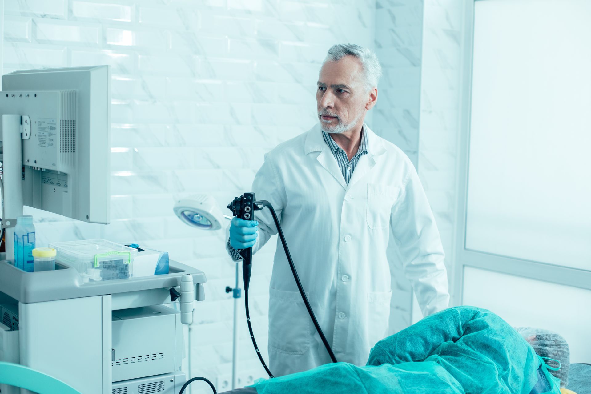 Doctor holding an endoscope beside a patient in a bright hospital room