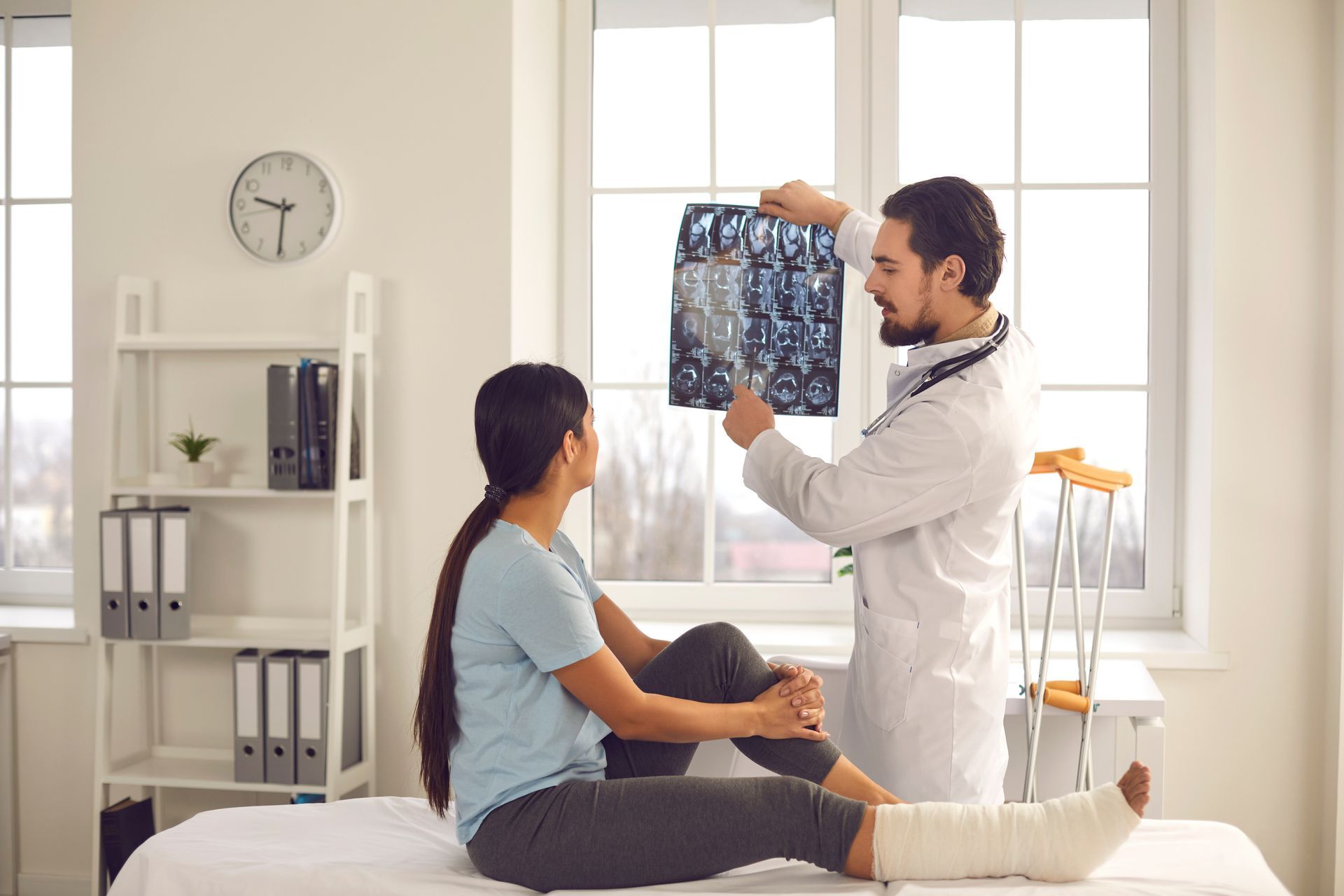 Doctor showing an X-ray to a seated patient in a bright exam room