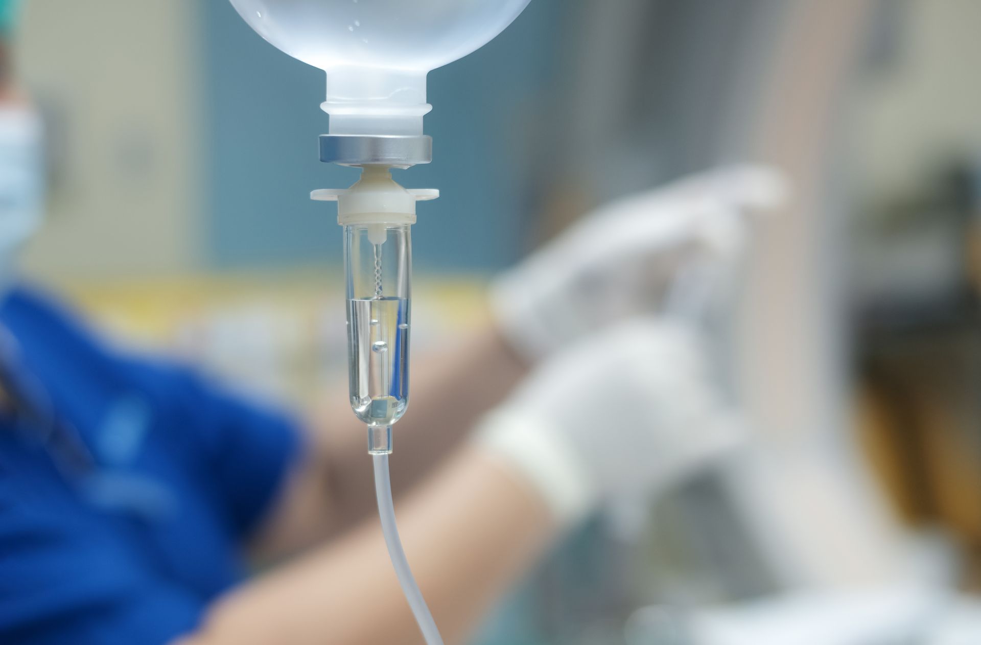 IV drip bag and tubing in a hospital with a blurred patient in the background