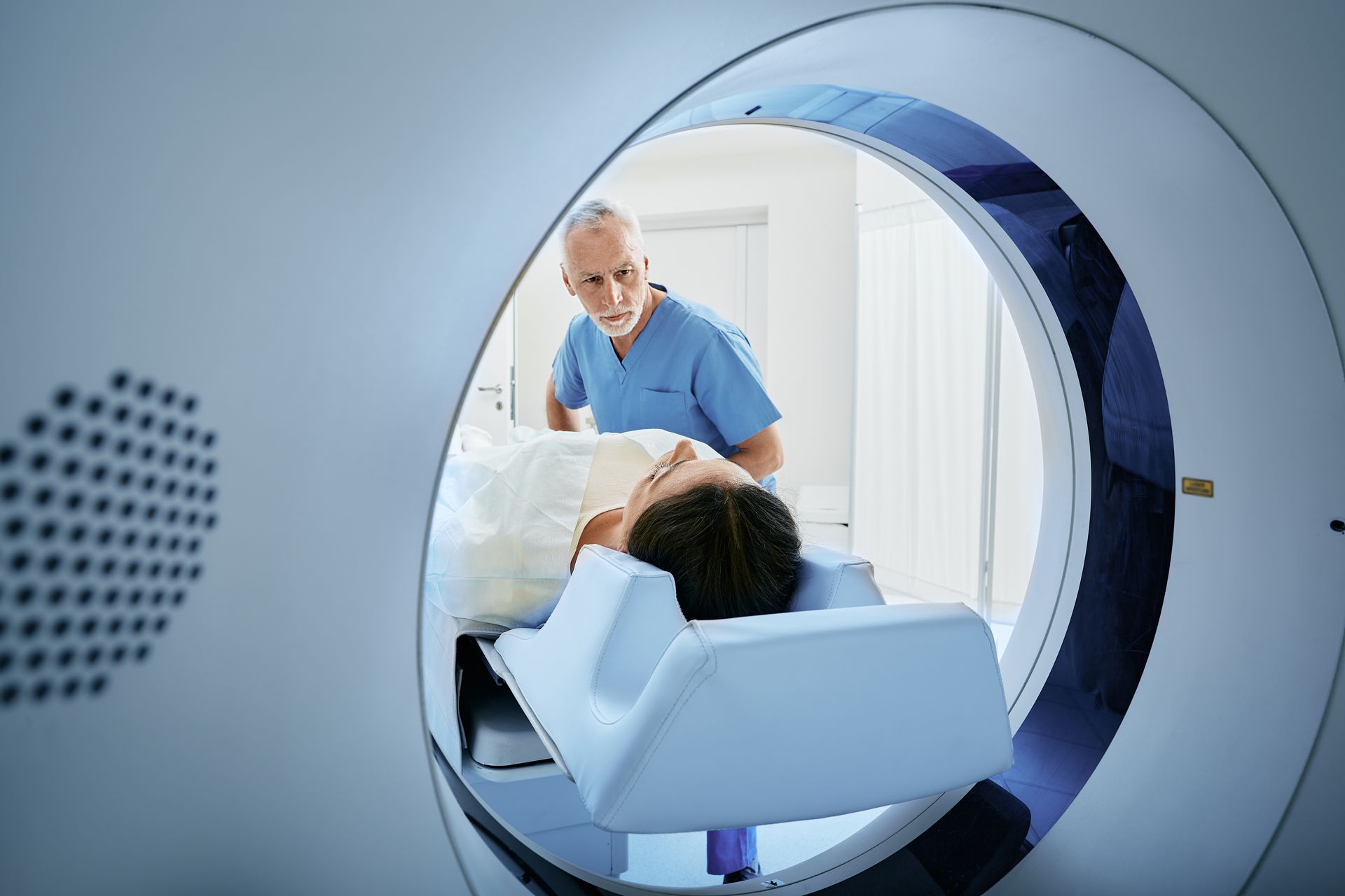 Patient entering MRI scanner with technician in a hospital room