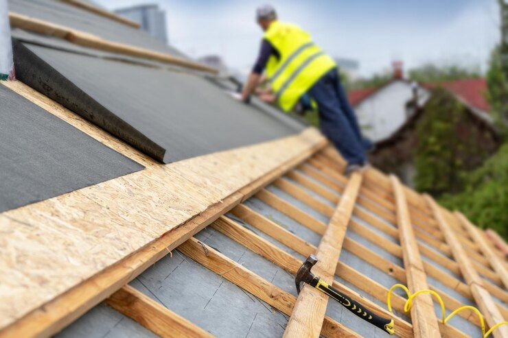 Roofers installing underlayment and wooden battens on a sloped roof