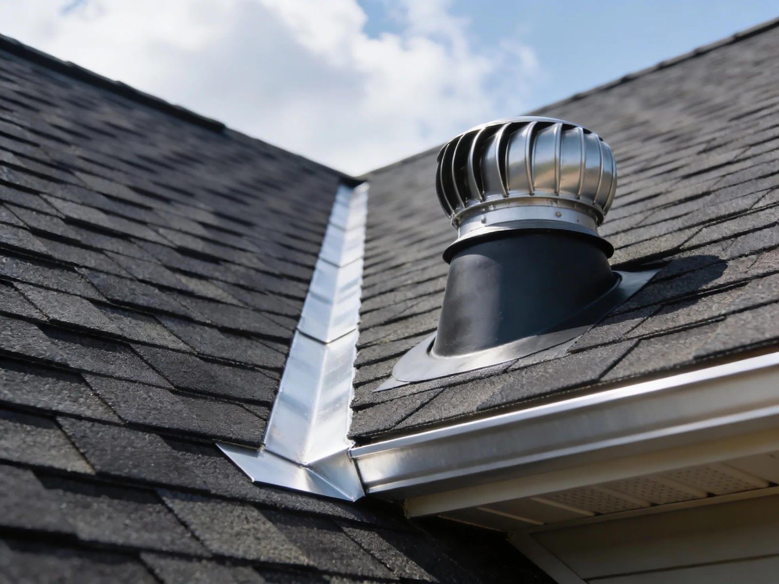 Roof shingle vent and flashing on a house roof under blue sky