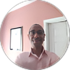 Smiling man in a pink shirt standing in a room with pink walls and a window mirror