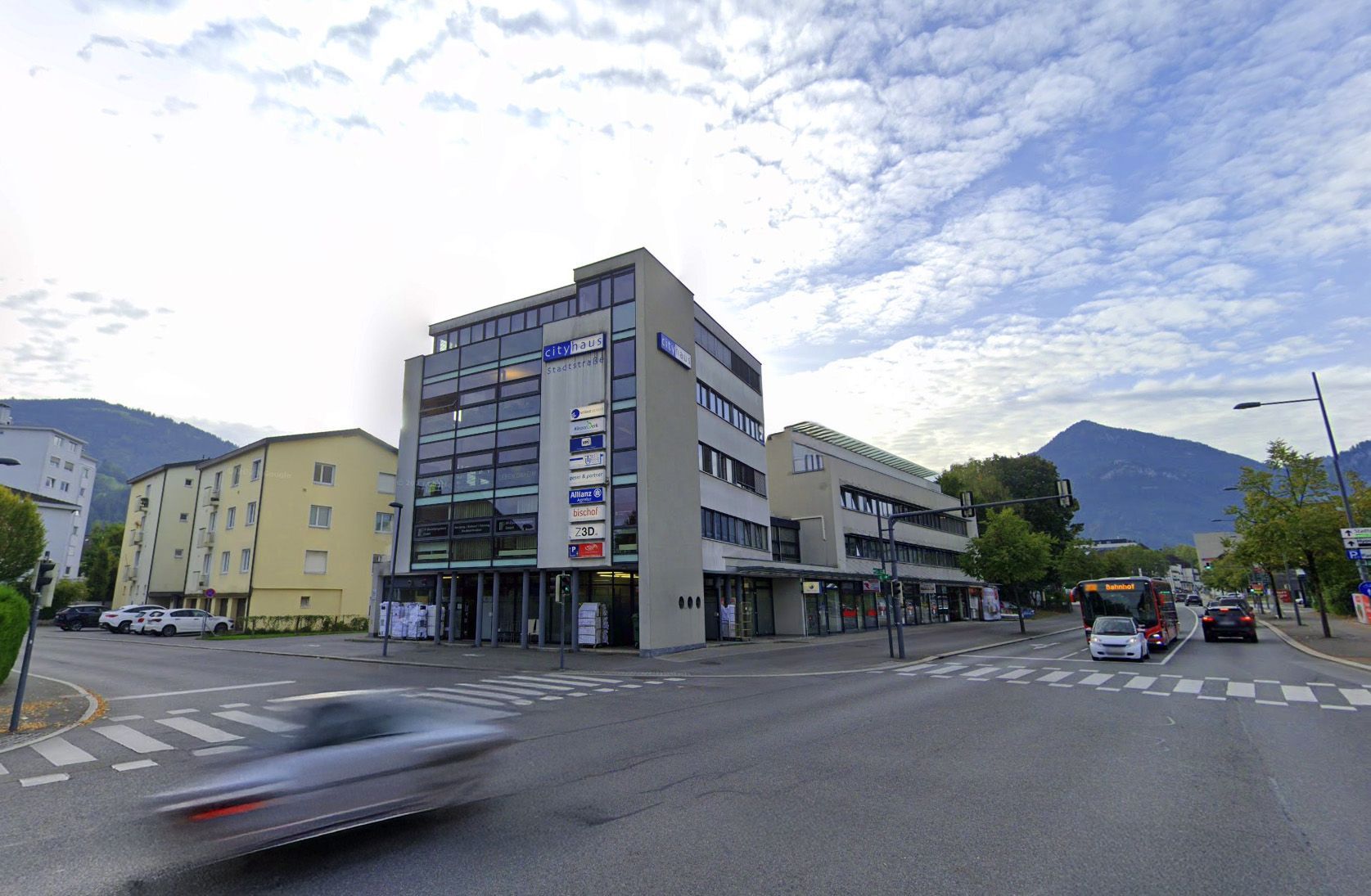 Ein Auto fährt eine Straße vor einem großen Gebäude entlang. Neuer Standort Kalb Baumanagement.