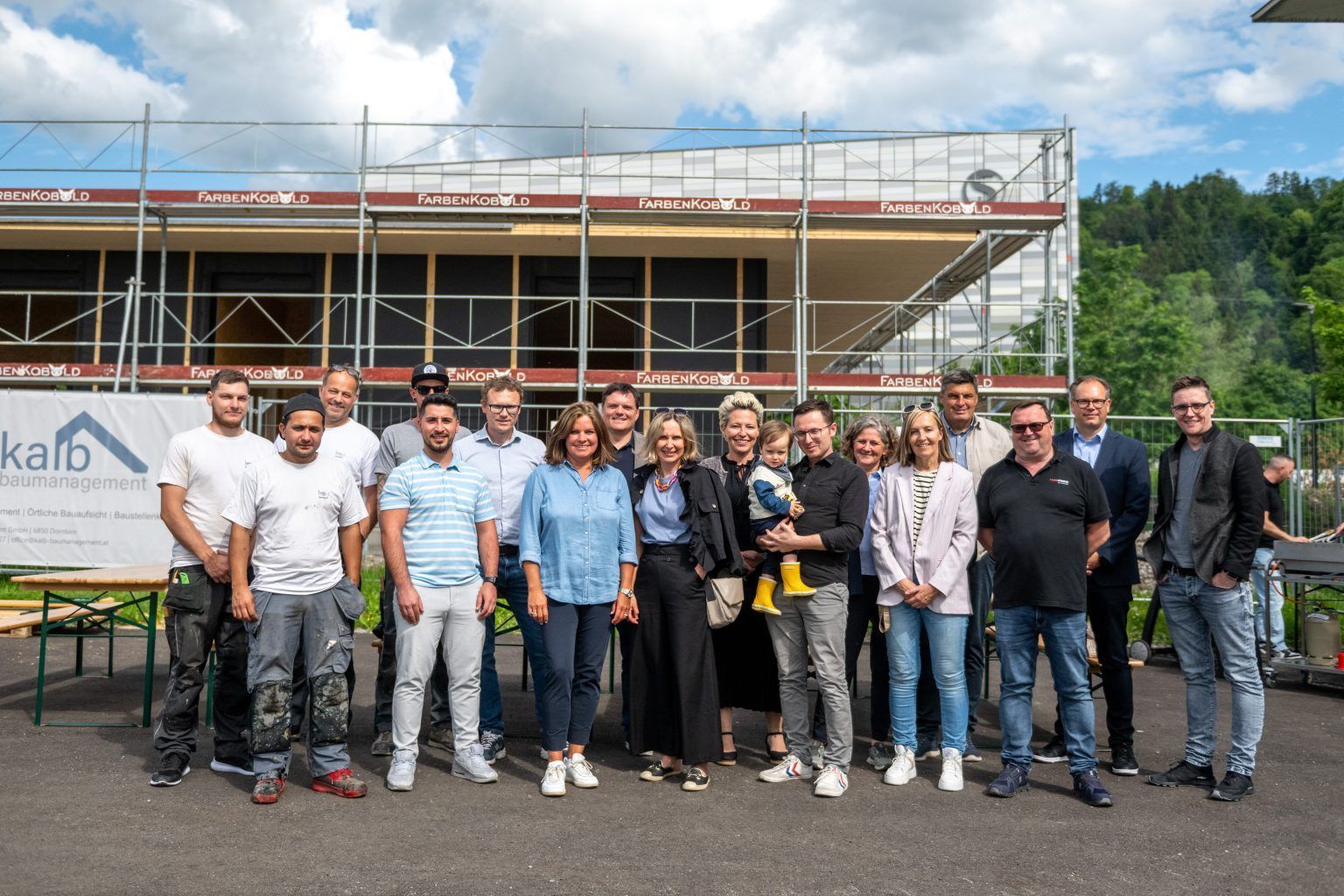 Eine Gruppe von Menschen posiert vor einem im Bau befindlichen Gebäude für ein Foto.