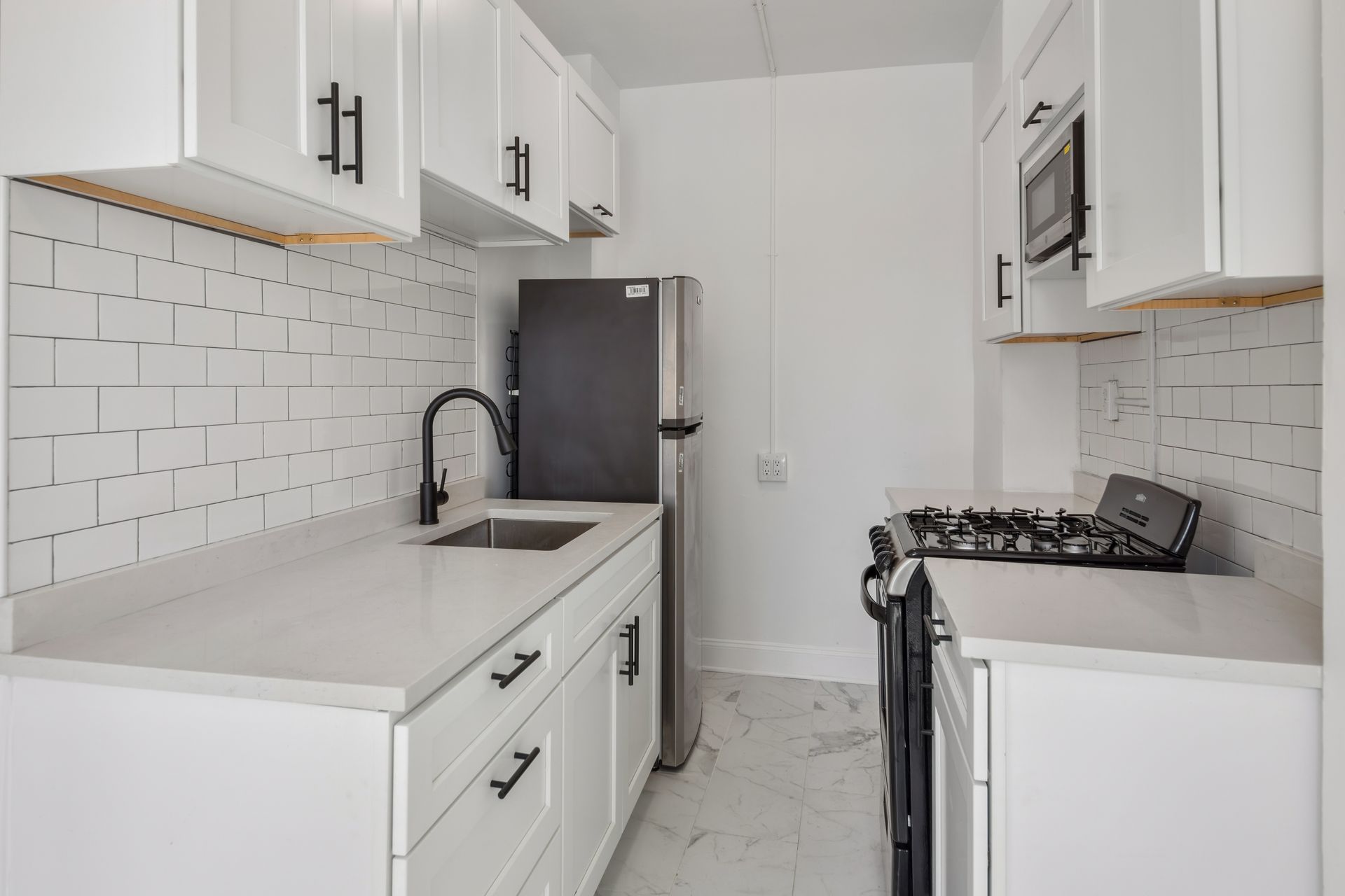White kitchen with stainless steel appliances and black accents.