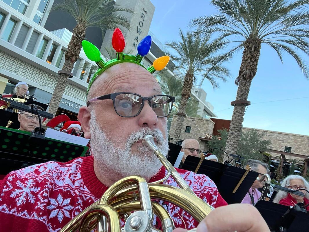 French horn player at the Christmas concert in a red and white sweater and wearing a crown of christmas lights.