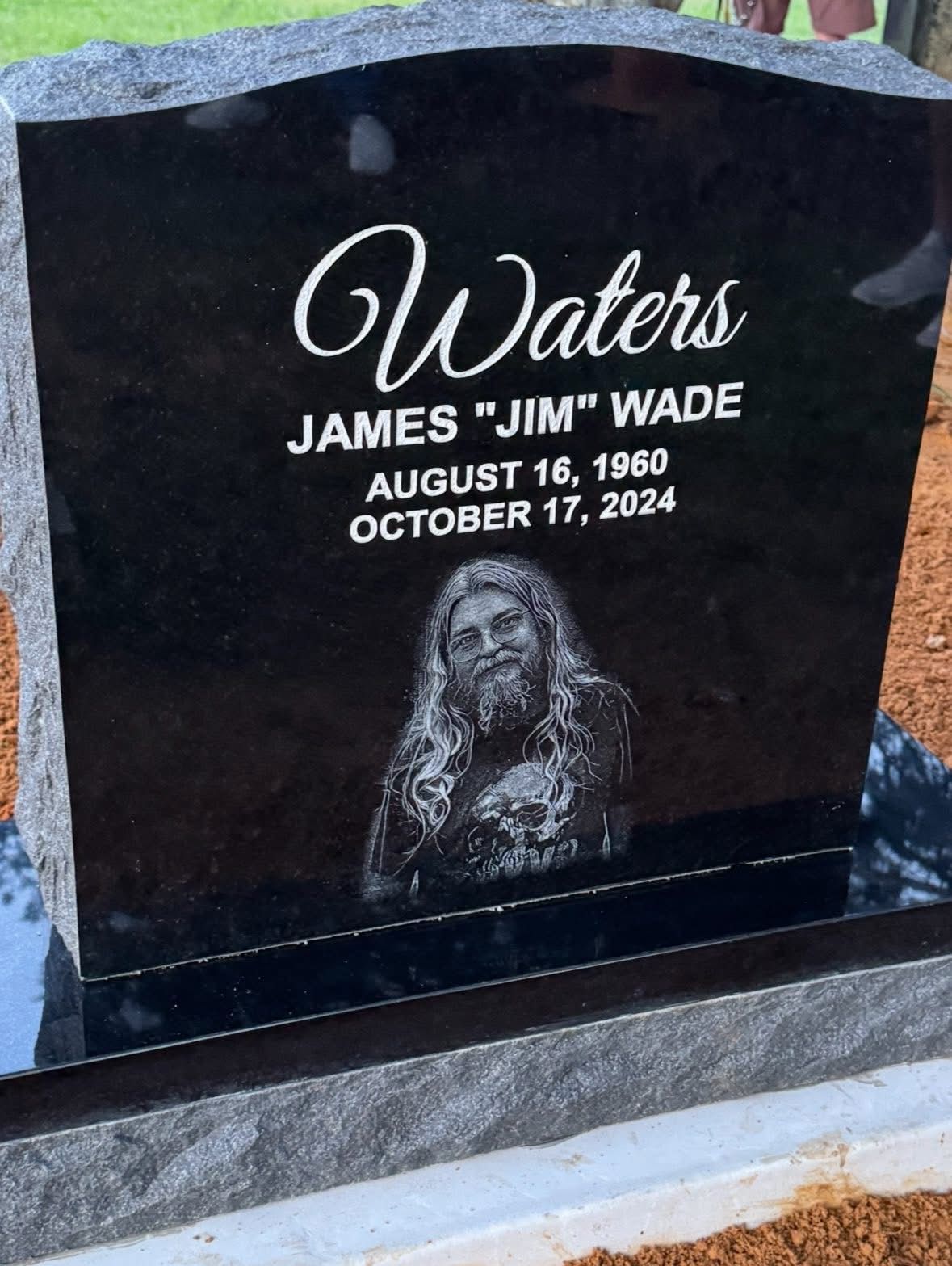 Black granite gravestone with “Waters” and “James ‘Jim’ Wade,” dated Aug. 16, 1920–Oct. 17, 2024.
