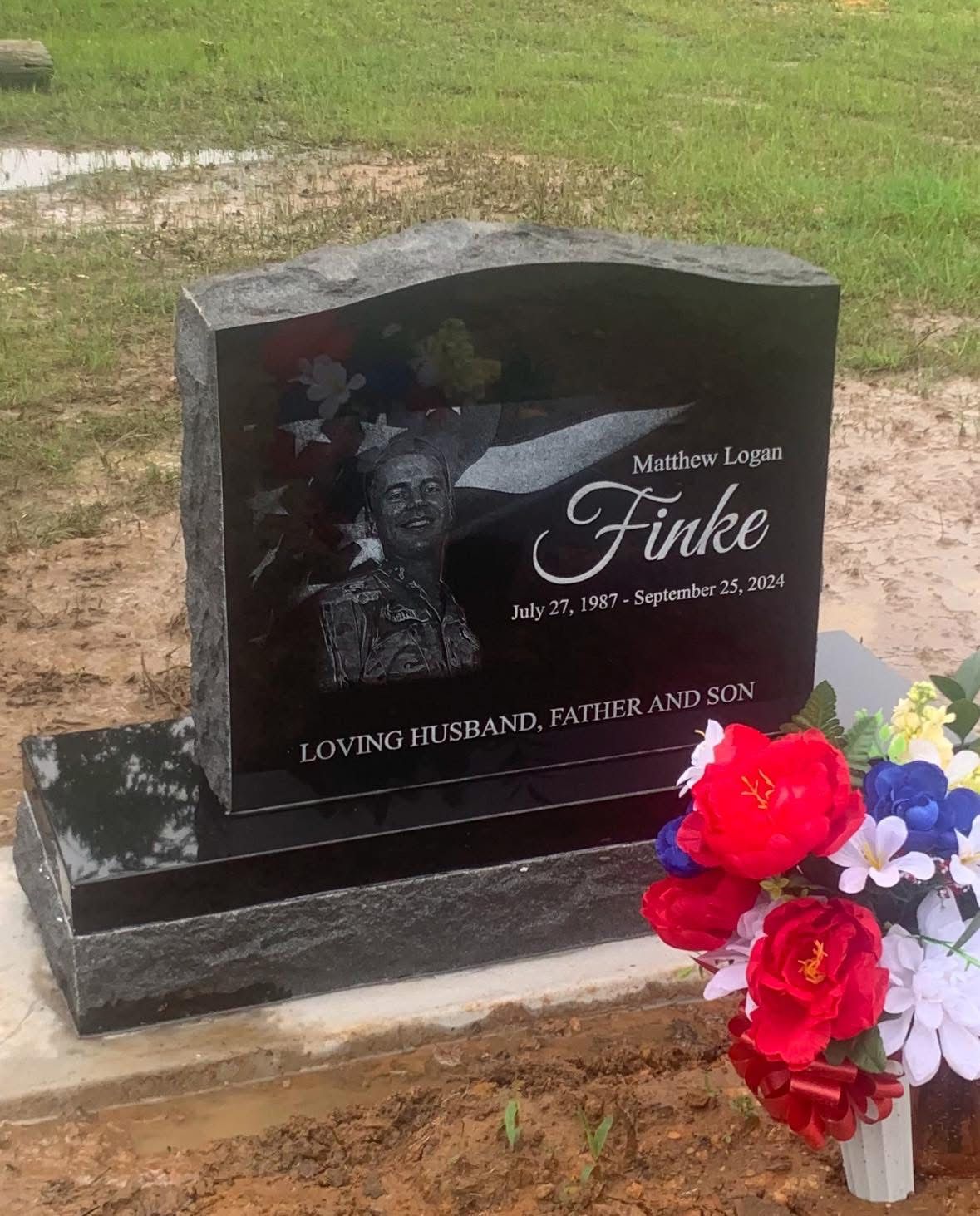 Gravestone with engraved portrait and flowers in a grassy cemetery area