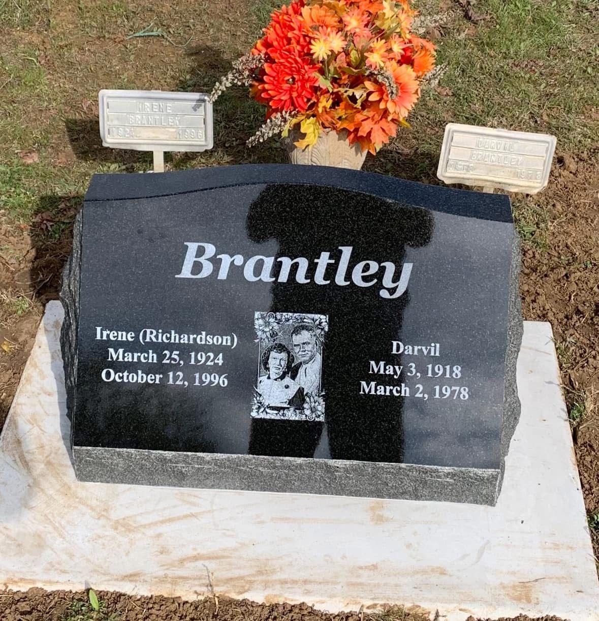 Brantley gravestone with flowers and two memorial plaques on a white base