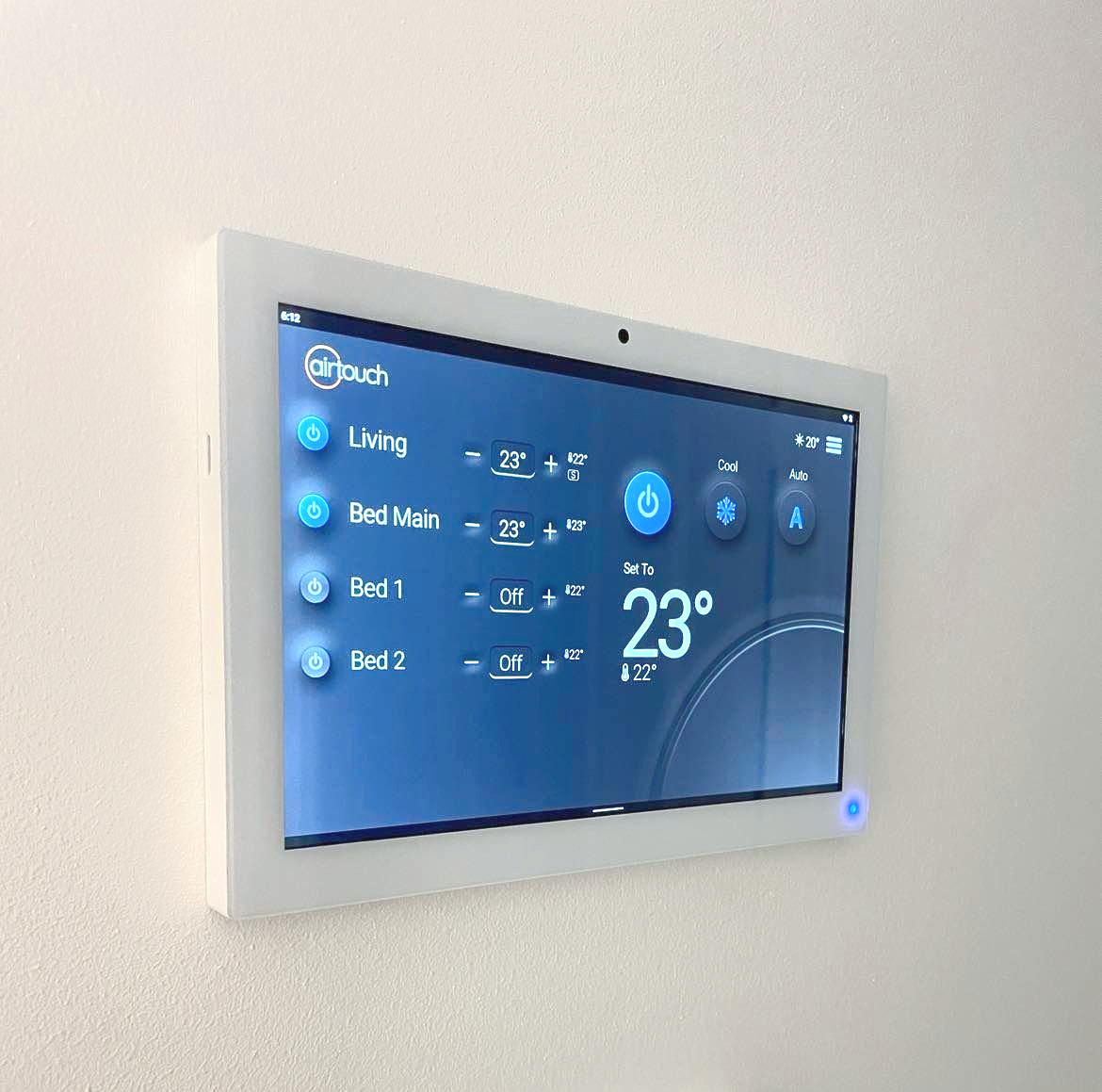 Wall-mounted touchscreen thermostat showing 23°C in a white hallway above a light switch — JF Air Conditioning Pty Ltd in Edgeworth, NSW