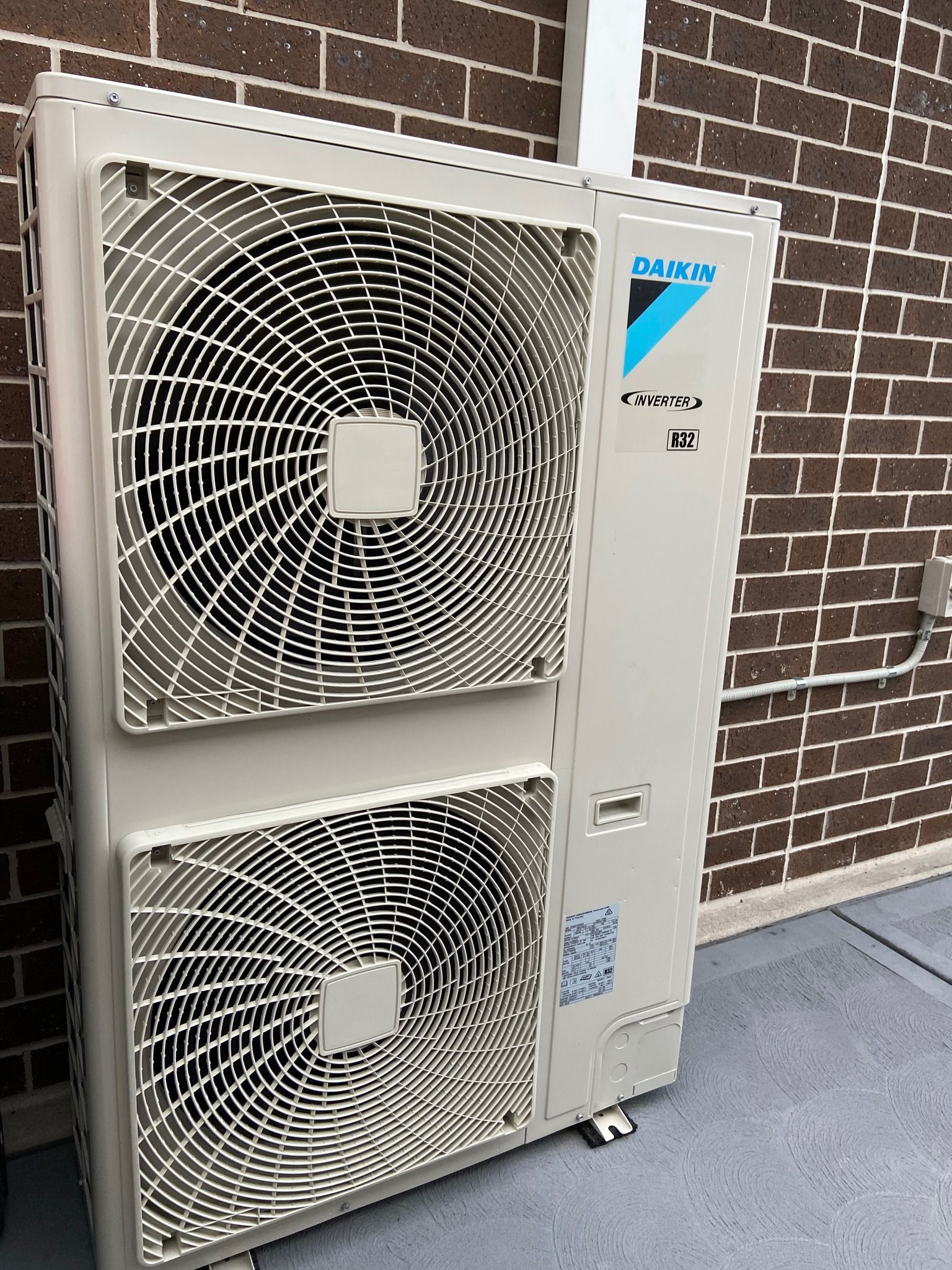 Two large outdoor air conditioner units mounted beside a brick wall — JF Air Conditioning Pty Ltd in Edgeworth, NSW