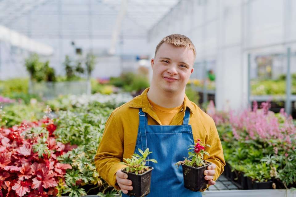  young boy with Down syndrome caring a garden