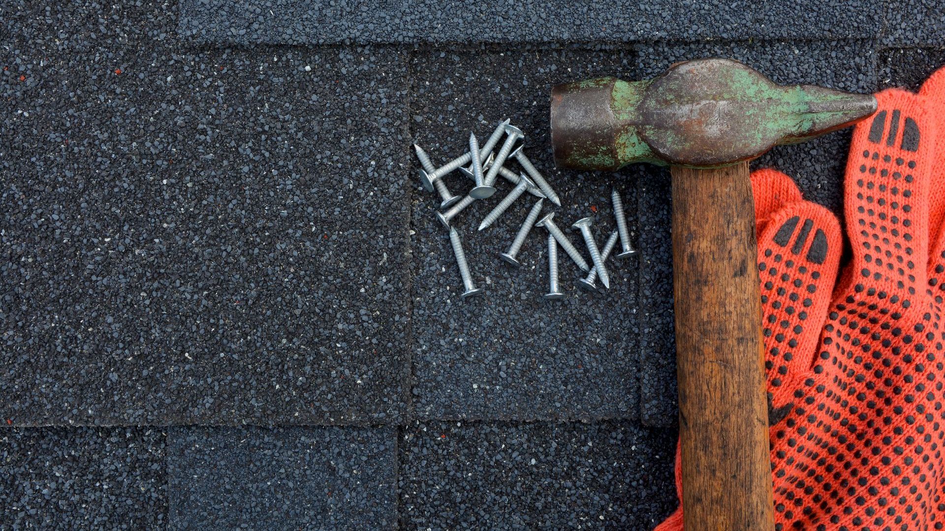 A hammer and nails are sitting on top of a roof.