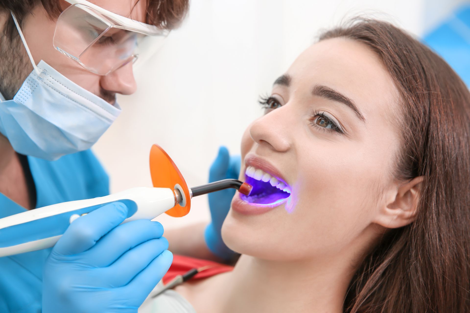 A dentist is using a UV curing light to harden a composite resin filling.