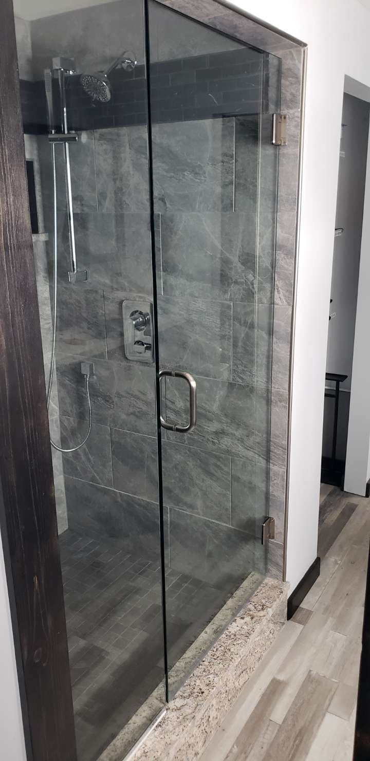 A bathroom with a walk in shower with a glass door.