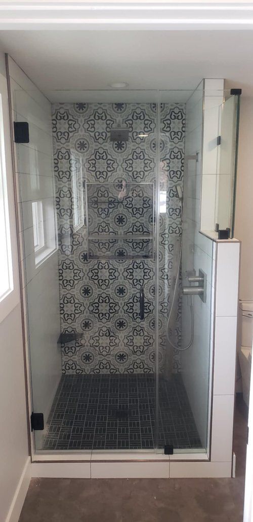 A bathroom with a walk in shower with a glass door.
