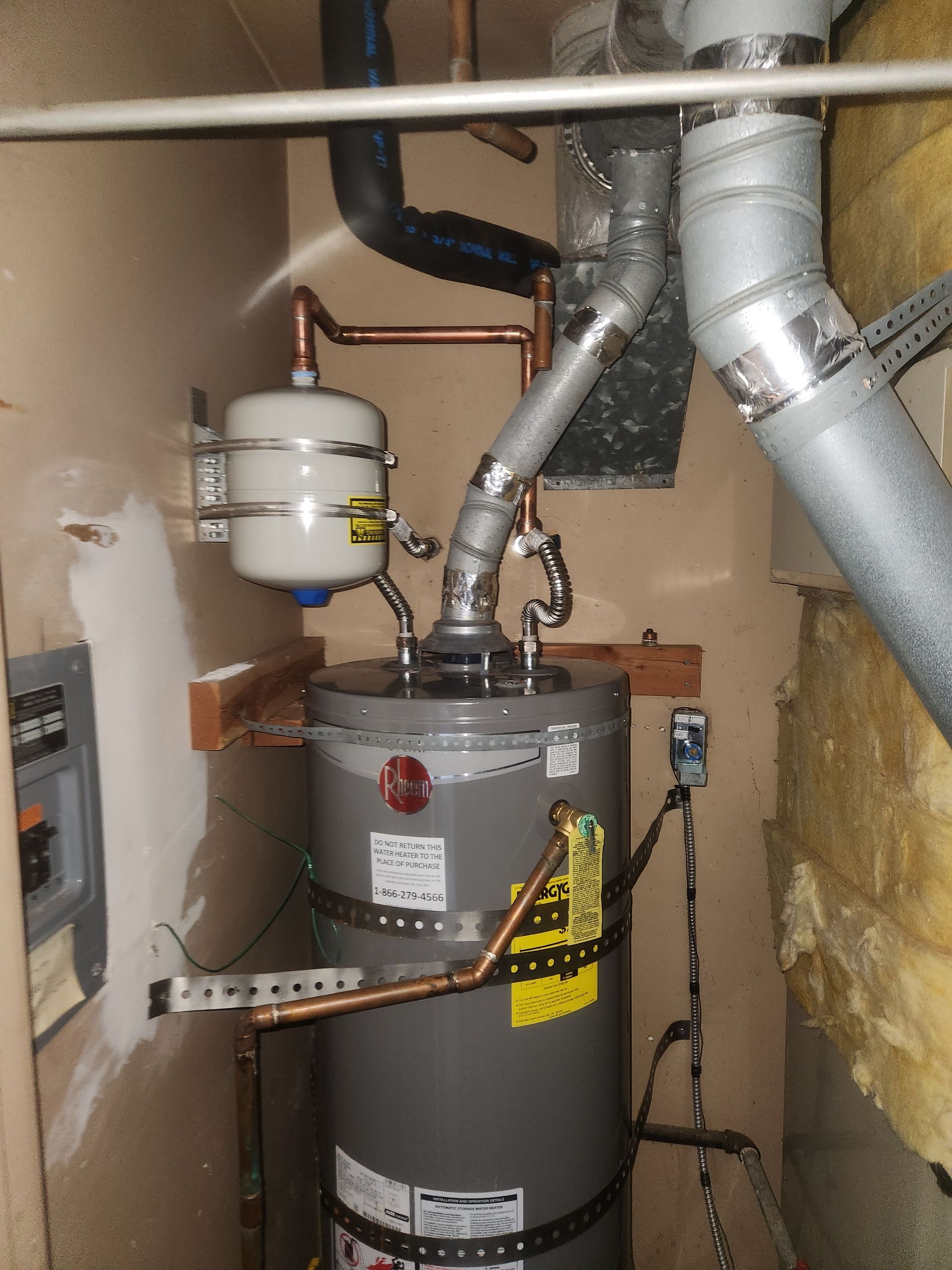 Water heater and plumbing pipes in a utility closet, with insulation and ductwork nearby.