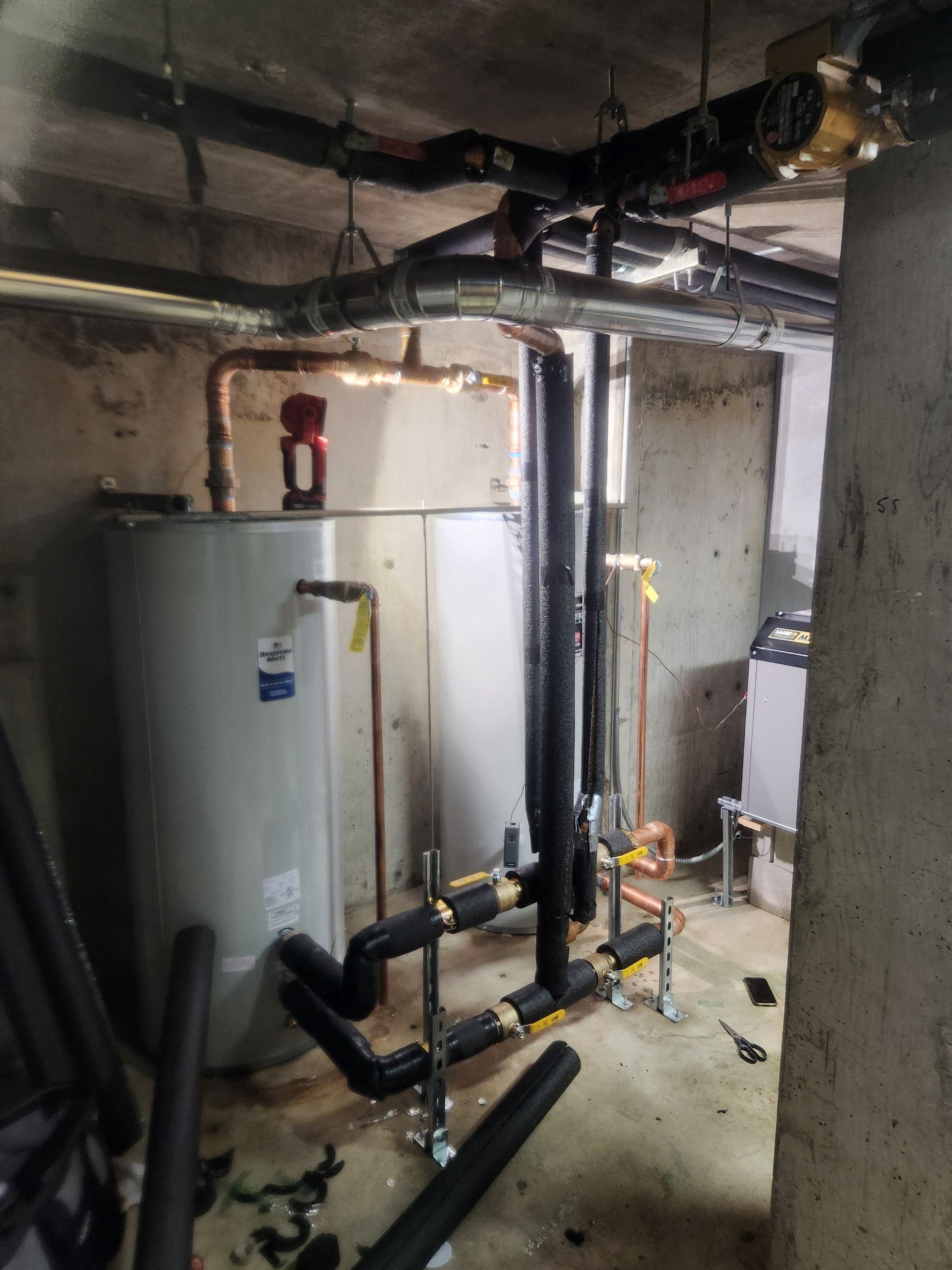 Basement utility room with water heater, exposed pipes, and heating equipment