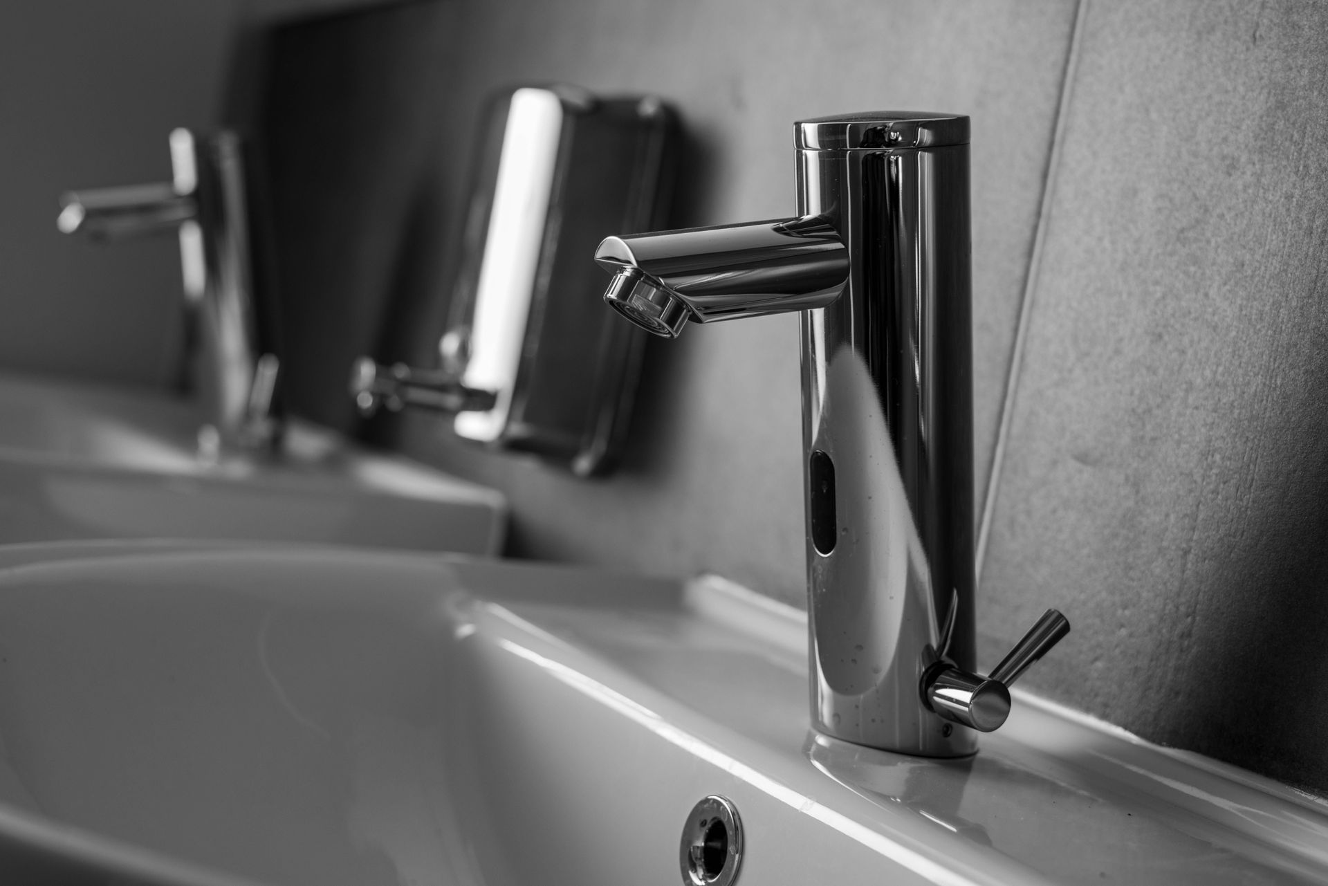Chrome bathroom faucets over a sink in black and white