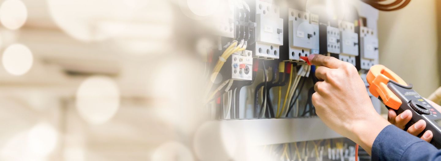 A man is working on an electrical panel with a screwdriver.