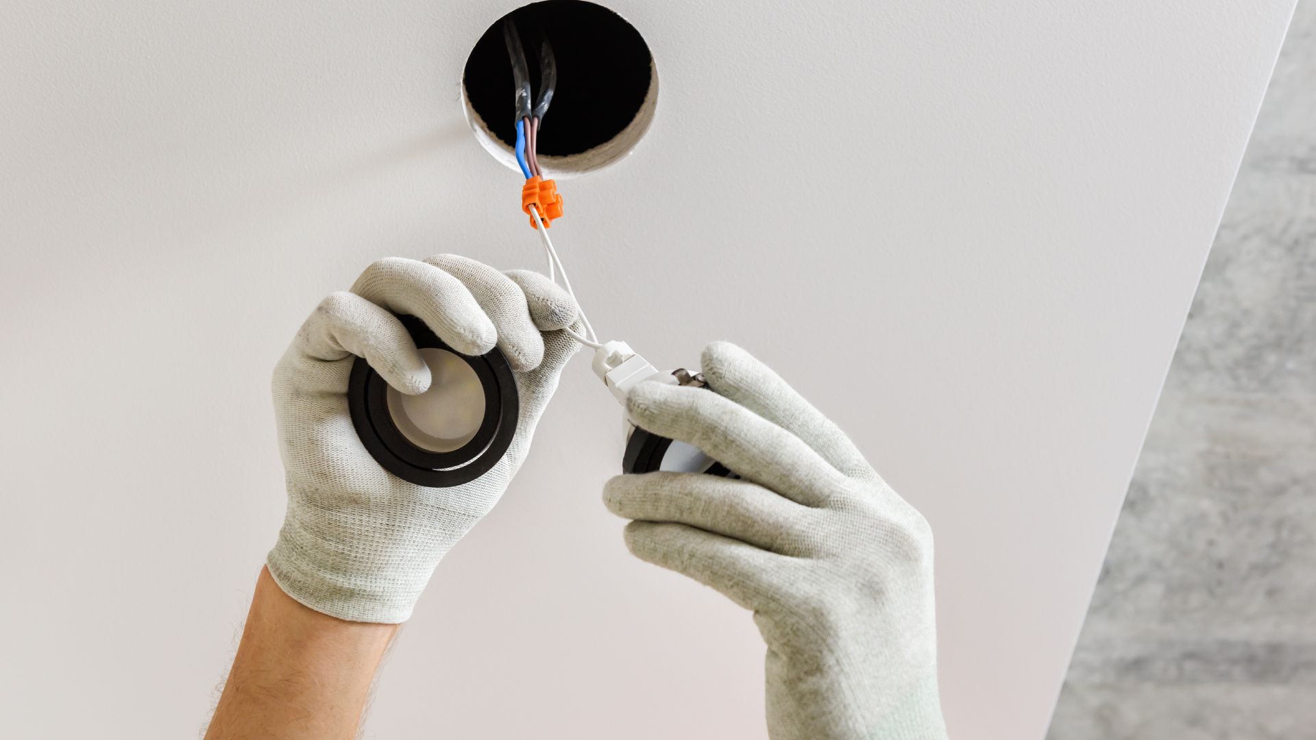 A person is installing a light fixture in a ceiling.