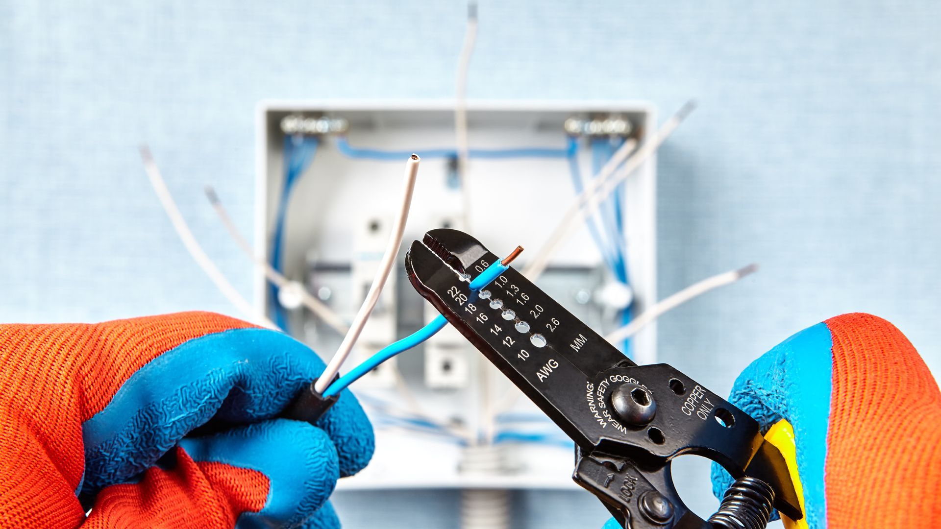 An electrician is cutting a wire with a wire stripper.