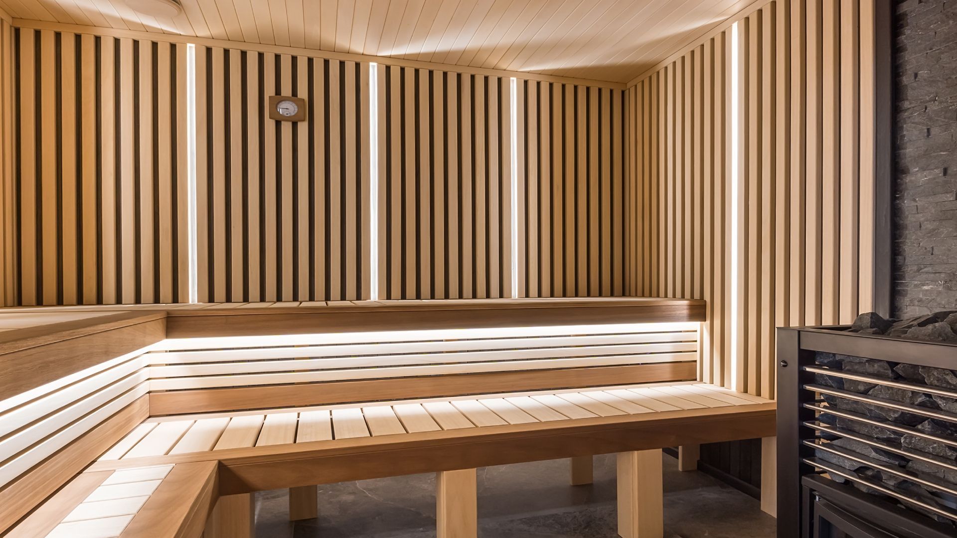 A wooden sauna with a lot of benches and lights on the walls.