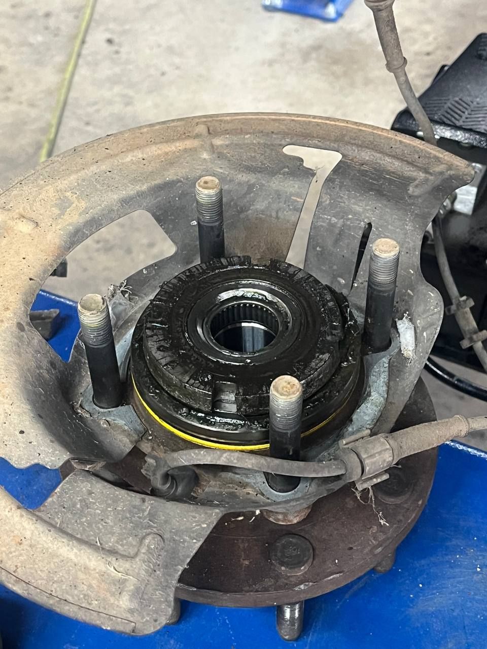 Detailed view of the disassembled front hub and steering knuckle during suspension repairs.