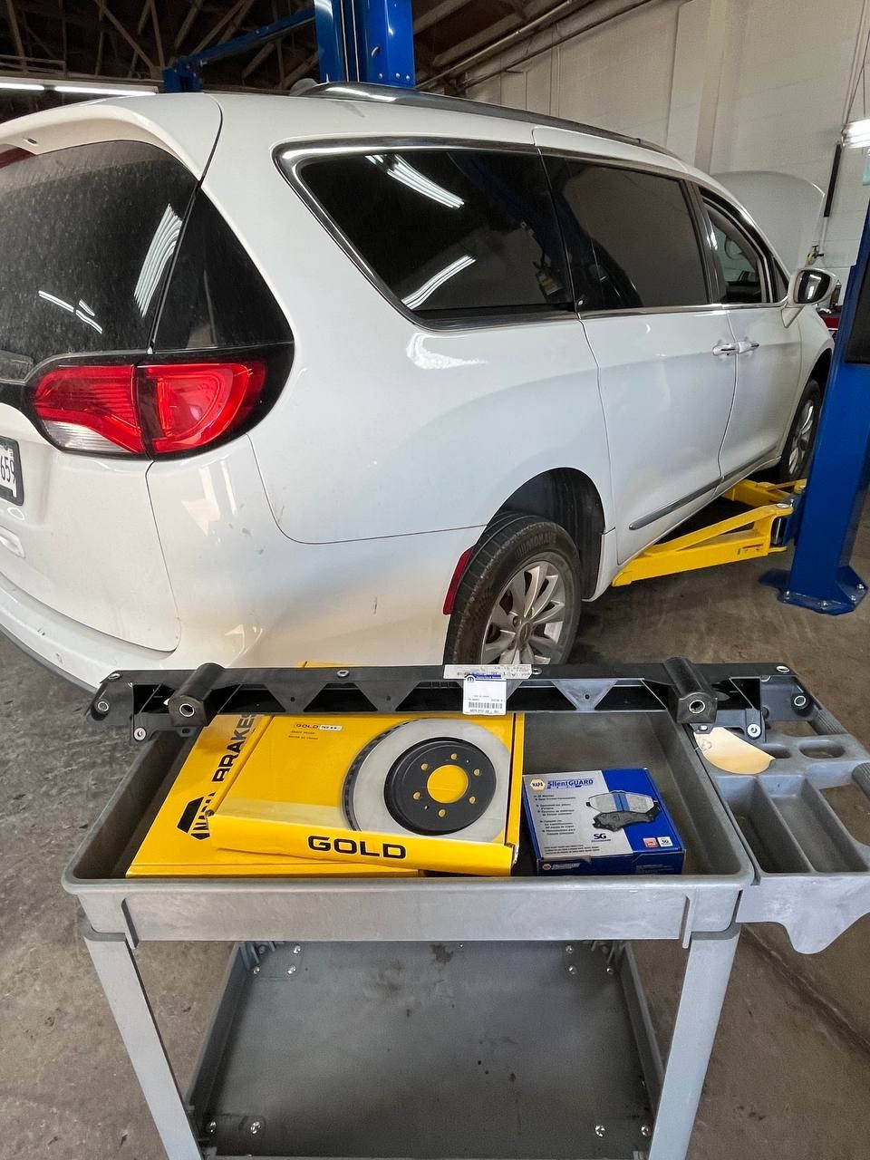 Parts staged for the Pacifica included the new OEM lower radiator support and brake components while repairs were underway.