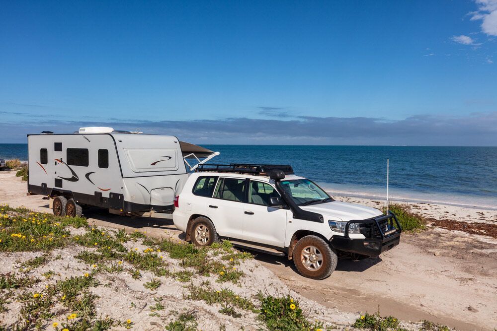 A White Suv is Towing a Trailer on the Beach — Activate Auto Electrics & Air Conditioning In Caloundra, QLD